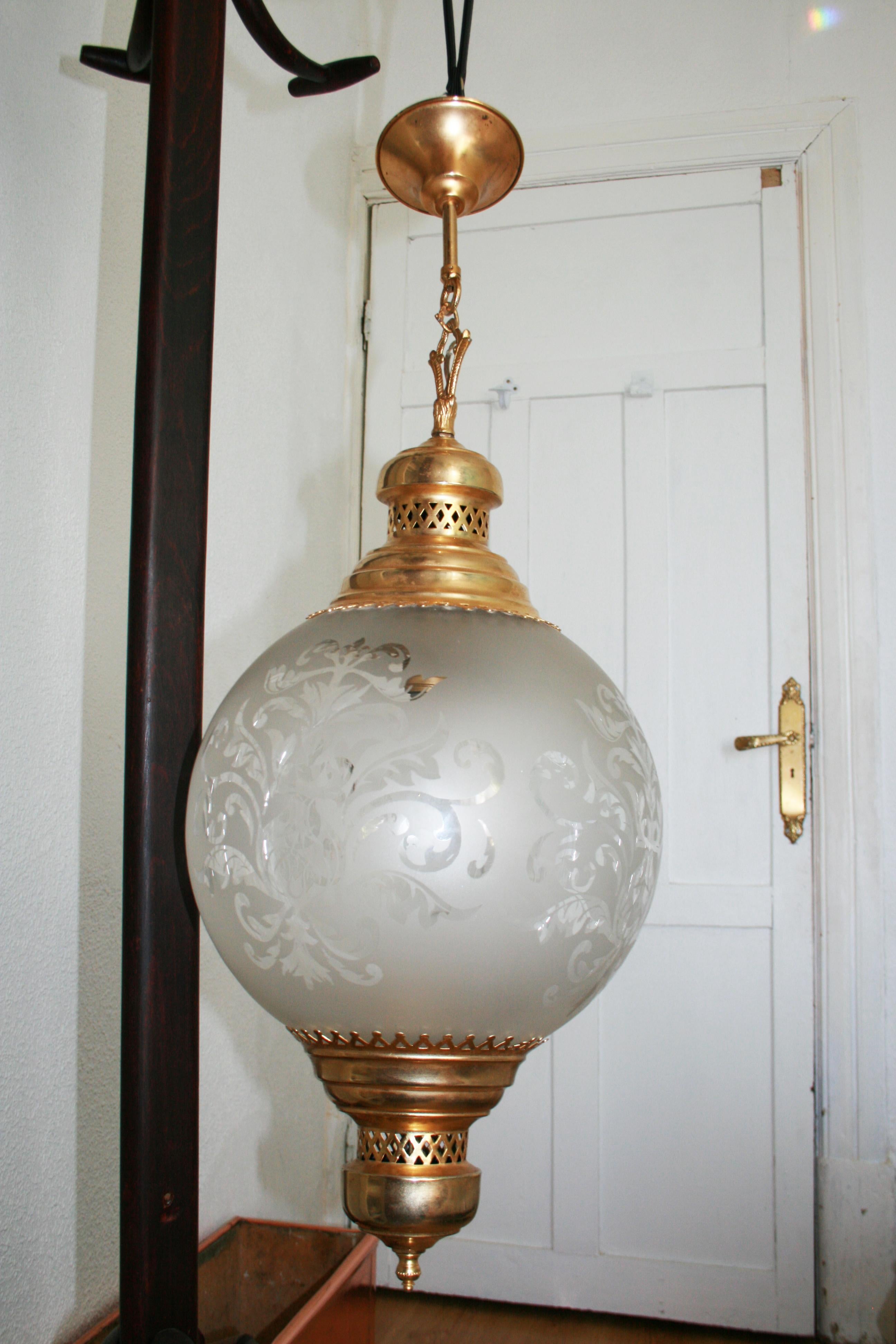 Mid-Century Modern brass chandelier, pendant or lantern with engraved crystal globe surrounded by ornaments decorated with flowers, Italy, 1950s 

This beautiful lamp with some oriental and classical reminiscences is very large to be a crystal