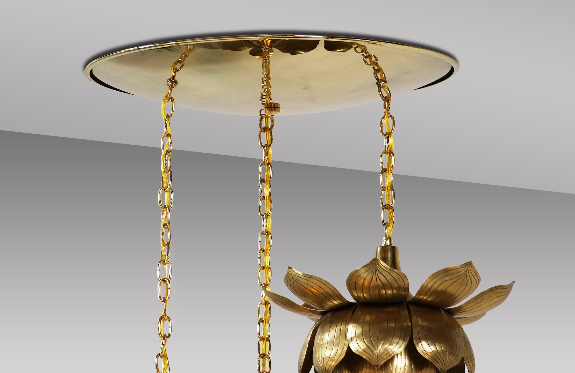 Sculptural lotus chandelier designed and manufactured by Feldman Lighting Co. in the United States, circa 1960s. This stunning flower pendant features three polished brass lotus flowers with a delicate patina hanging from chains attached to a