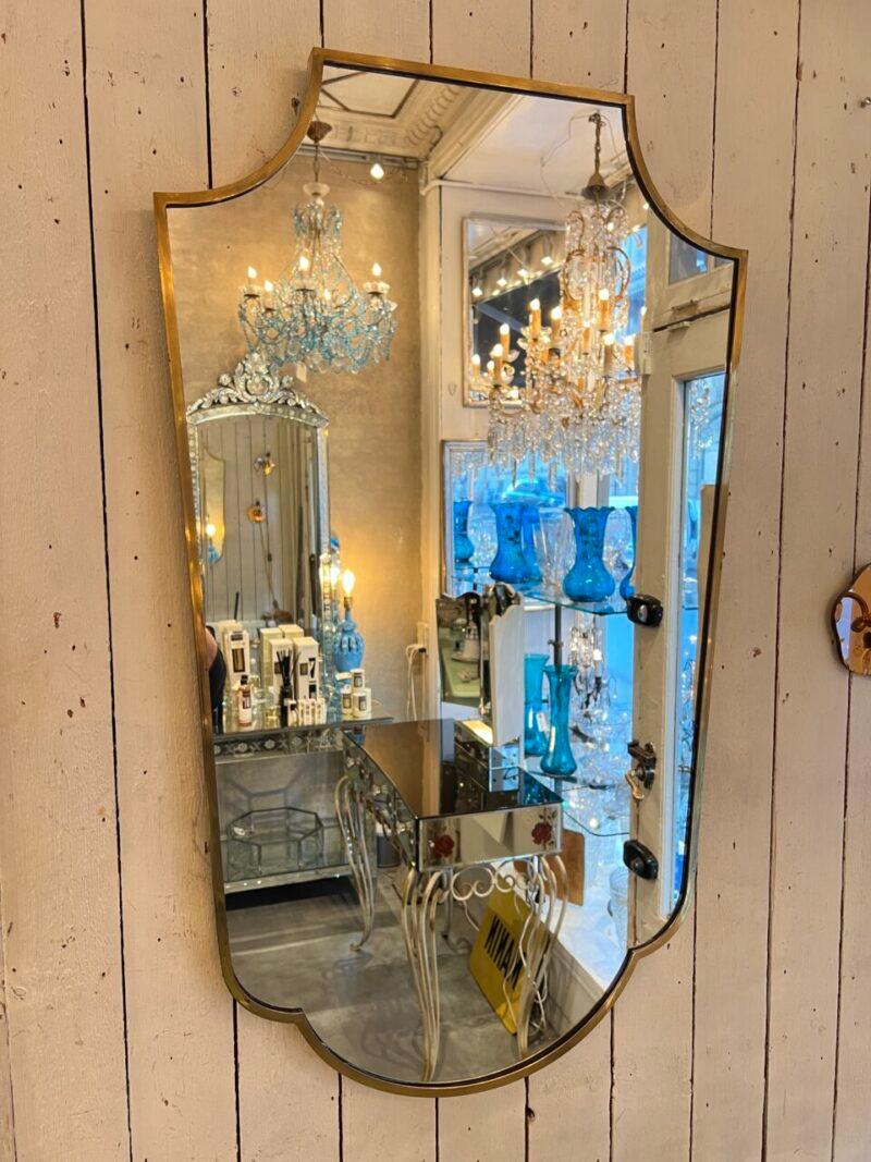 Mid-century beautiful Italian brass mirror. Wonderful almost shield like form.

Original mirror glass, and stylistically related to the Gio Ponti’s famous designs.

The mirror has suspension fittings mounted on the back.

Note the elegant wide brass