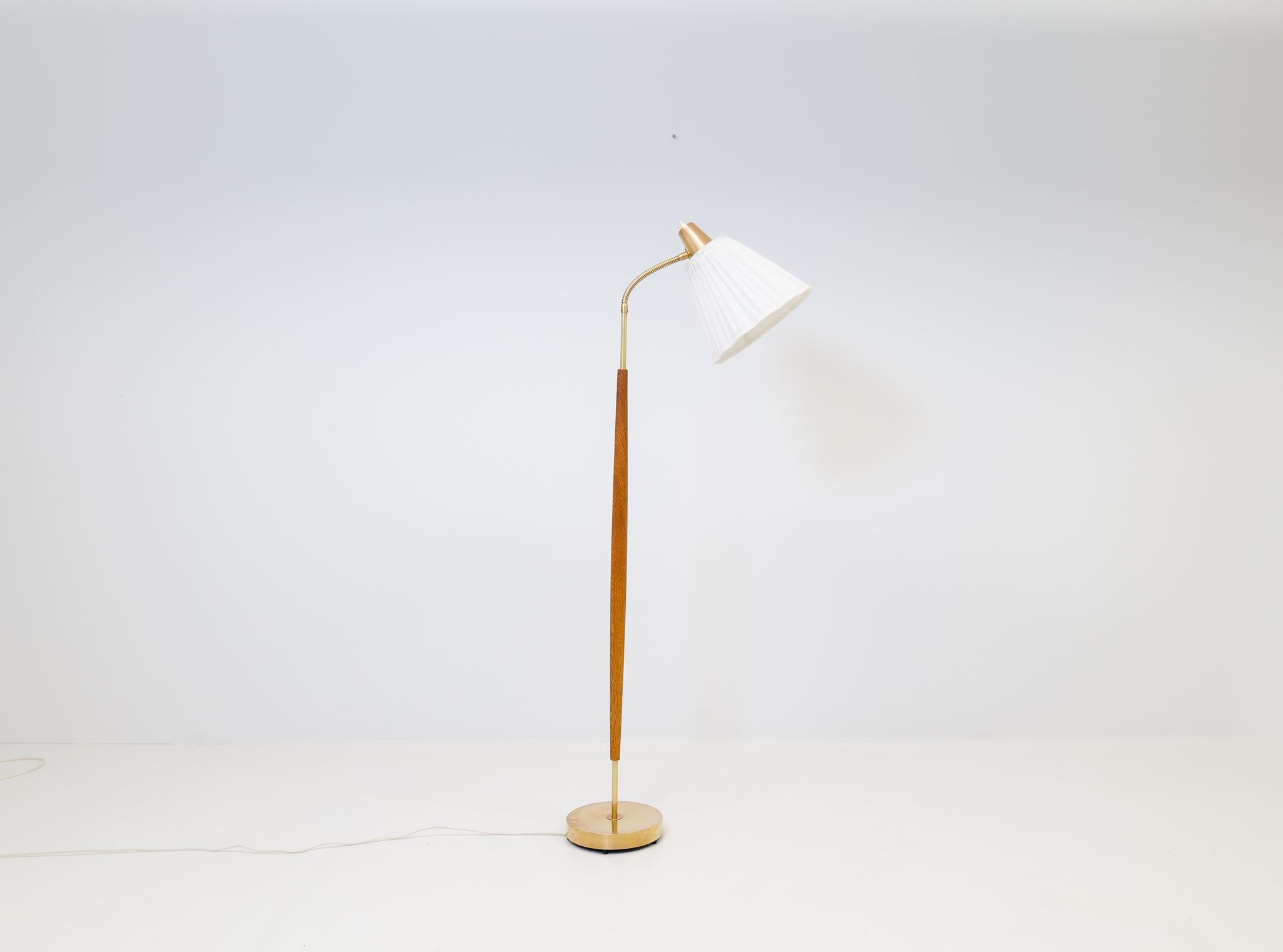 This lamp was made in Sweden at Falkenbergs Belysning. Wonderful, assembled brass combination with oak rod. The brass working well together with the sculptural and nicely grained oak. 

Good patinated brass, working condition. Old shade with some