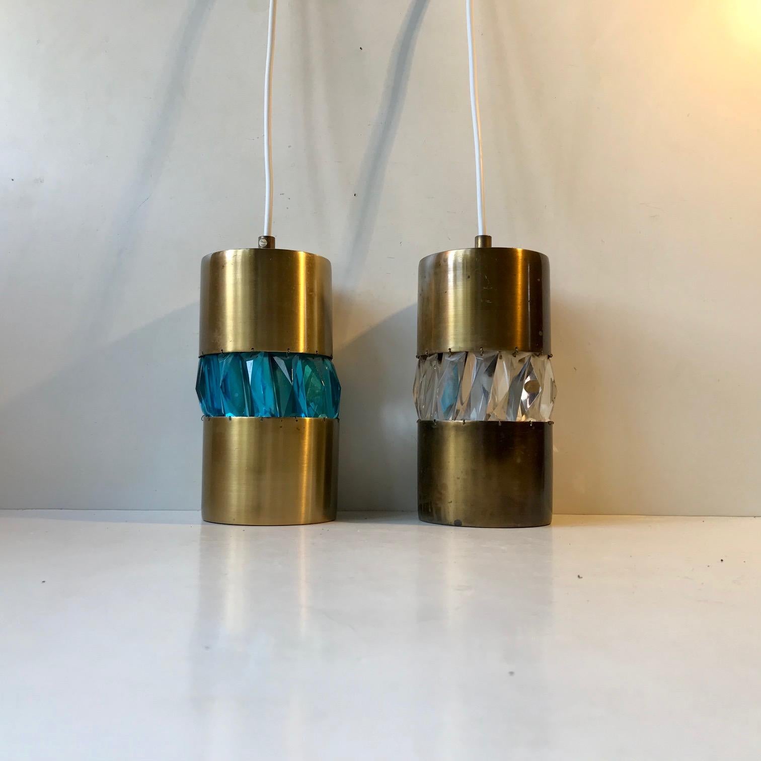 A pair of cylindrical pendant lights in solid patinated brass. Both with a perimeter band of Bohemian Crystals. One clear and one with light blue. A few of the crystals are labeled 'Bohemian Crystal' but whether these lights are made in Scandinavia