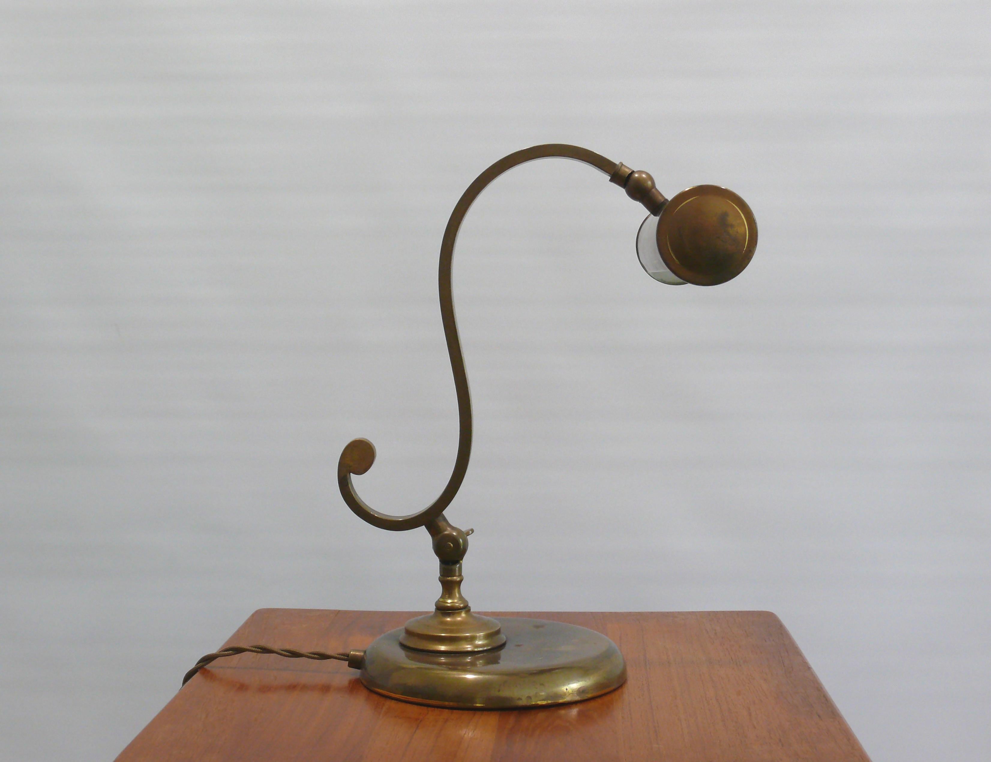 Very solid, heavy table lamp / piano lamp made of brass, probably from the 1950s in an Art Nouveau style. The lamp is made of brass with a heavy metal base. The umbrella and the arm can be adjusted. The light is switched on and off using a slide