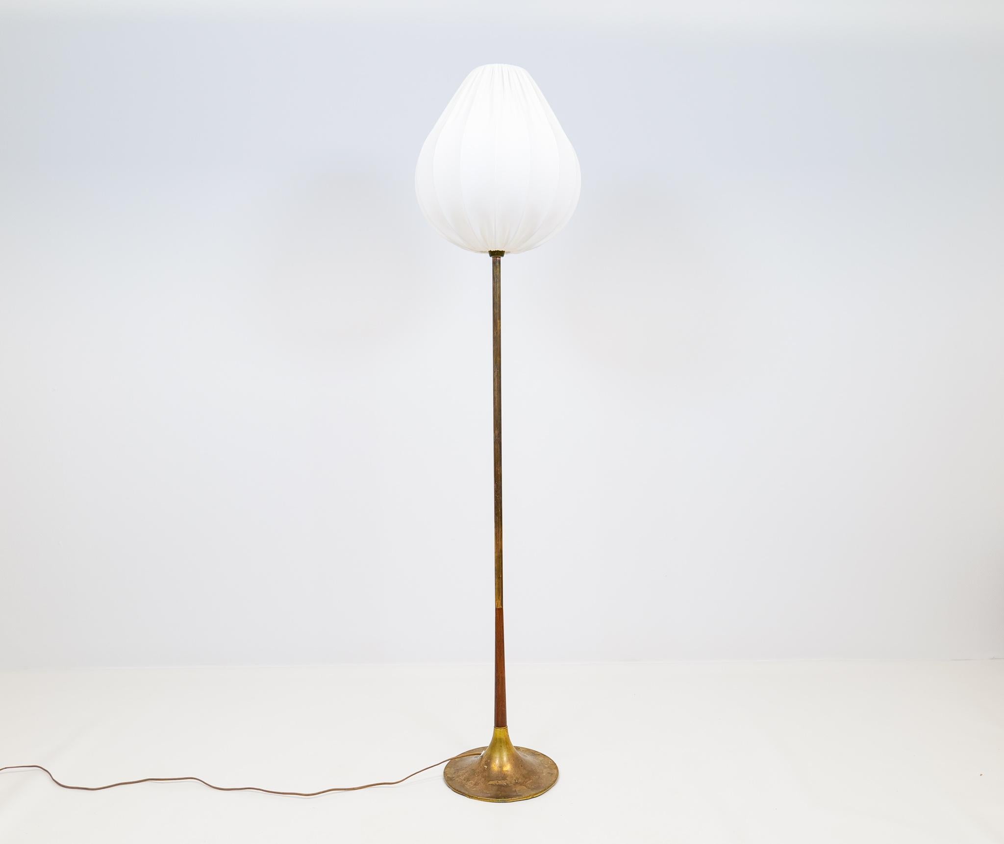 A gorgeous floor lamp made in brass with a trumpet shape like structure. The heavily patinated brass parts gives a wonderful look together with the small part of walnut. 

Good working condition with spots and signs of use on the base. The shade