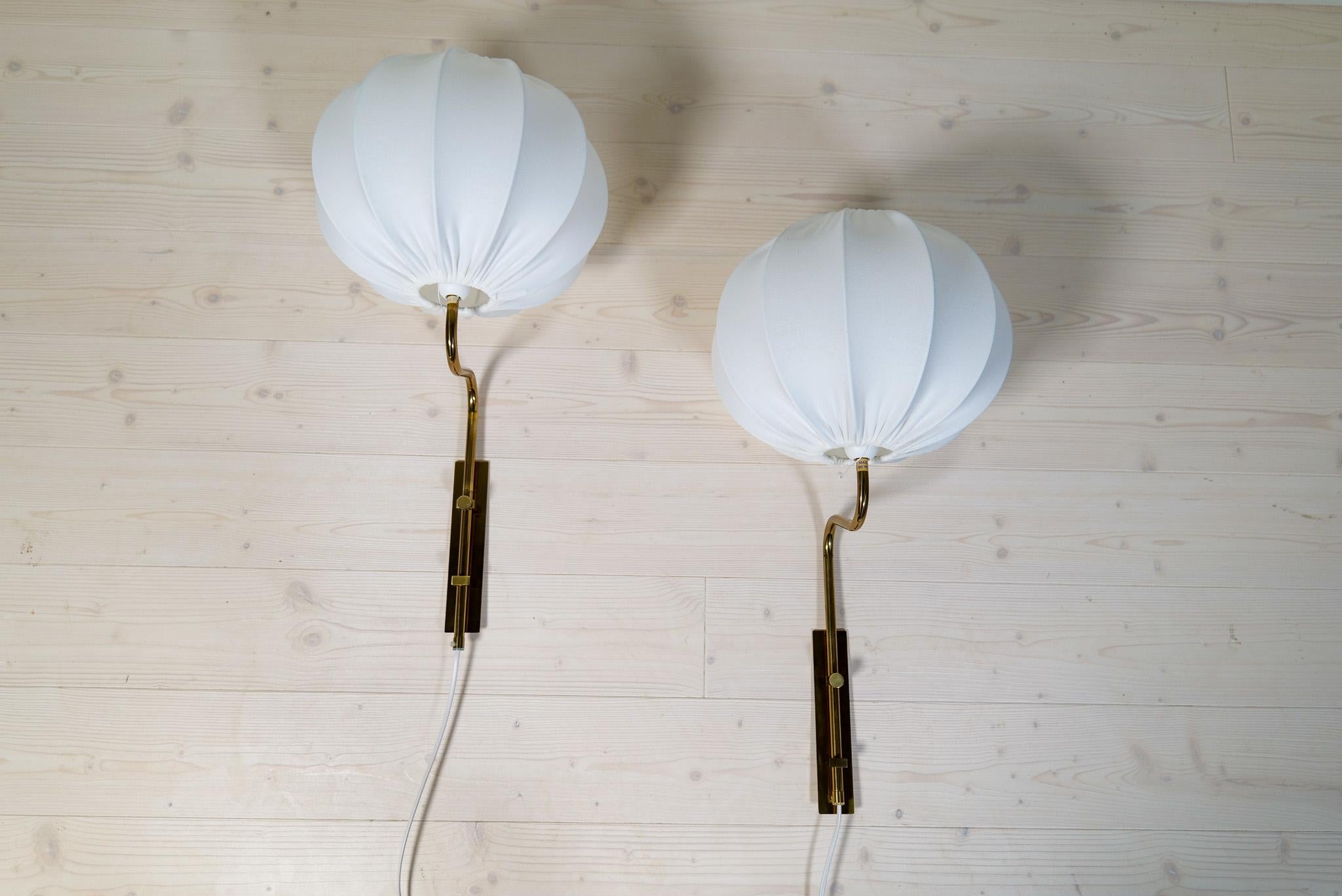 This set of 2 wall lights in brass were made at Bergboms Sweden during the late 1960s early 70s. These one is gifted with all new high quality cotton shades produced in Sweden and are typical of the 1950-60 era. They are adjustable in height and