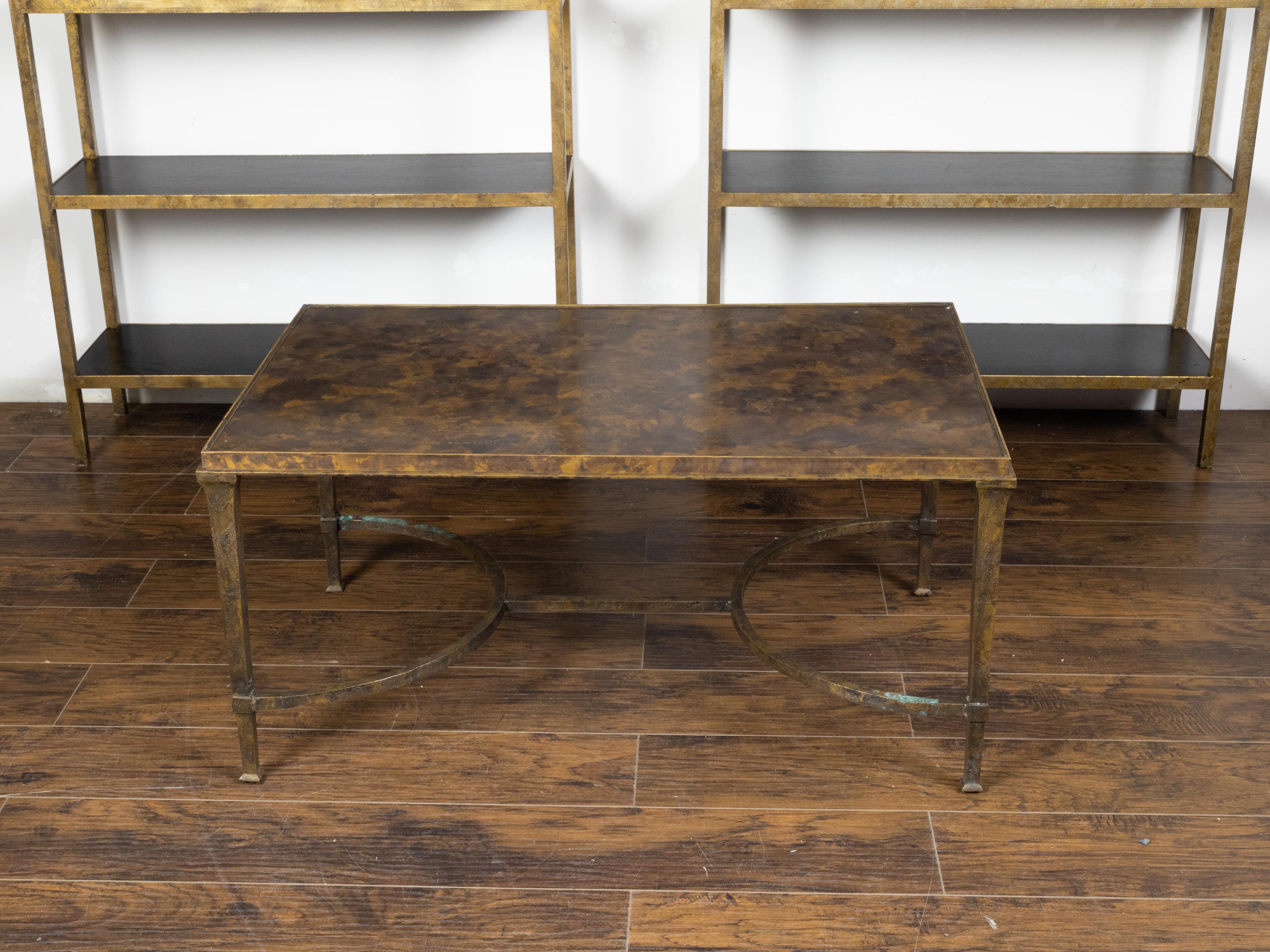 A vintage bronze coffee table from the mid 20th century, with marbleized top and double half-moon cross stretcher. Created during the midcentury period, this coffee table features a rectangular marbleized top sitting above an elegant bronze base