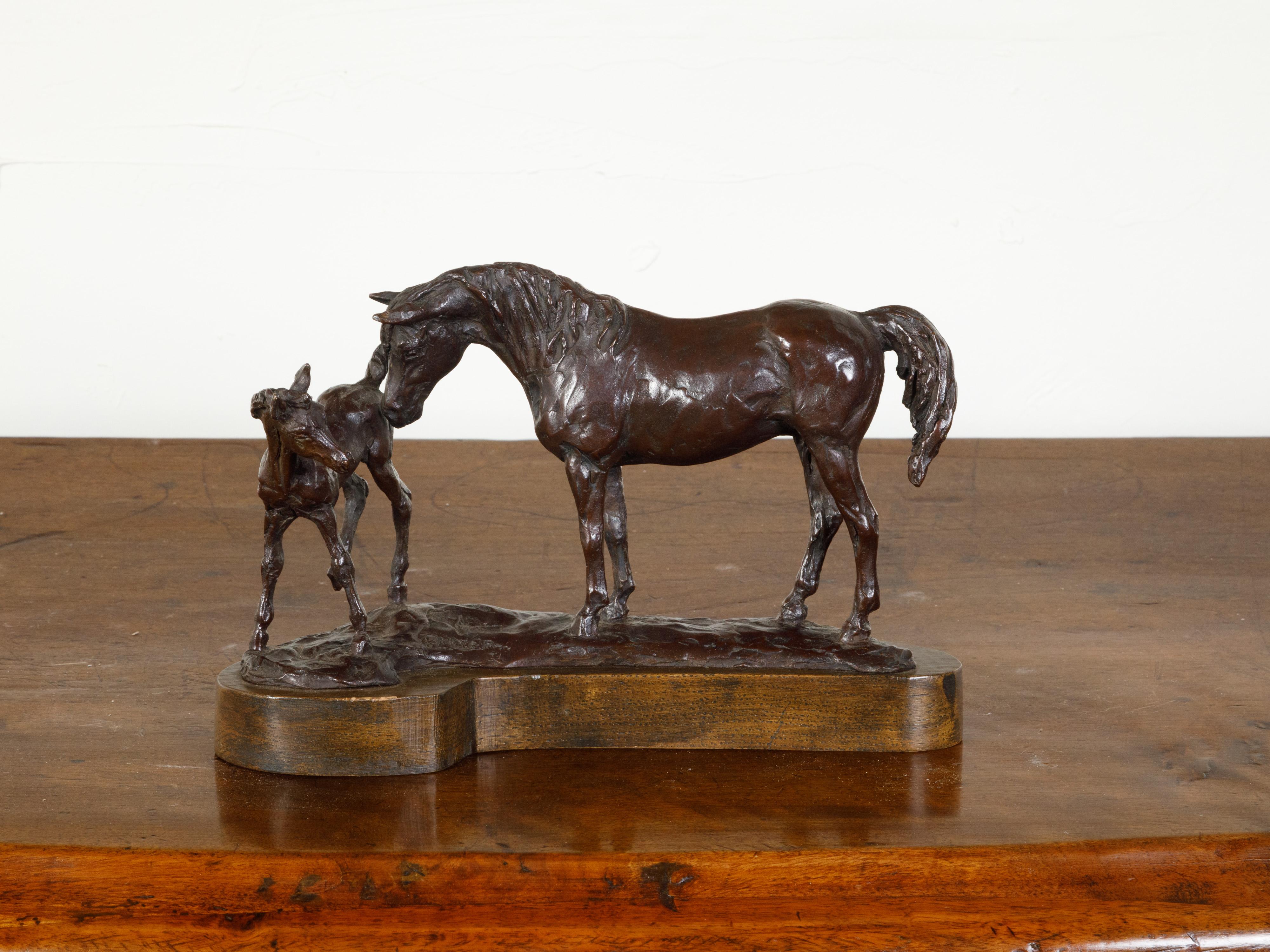A bronze sculpted group from the mid 20th century, depicting a mare and her foal. Cast in bronze during the Midcentury period, this sculpted group depicts a mare tenderly bending her head down to touch her foal. Lifting his hind legs up, the baby