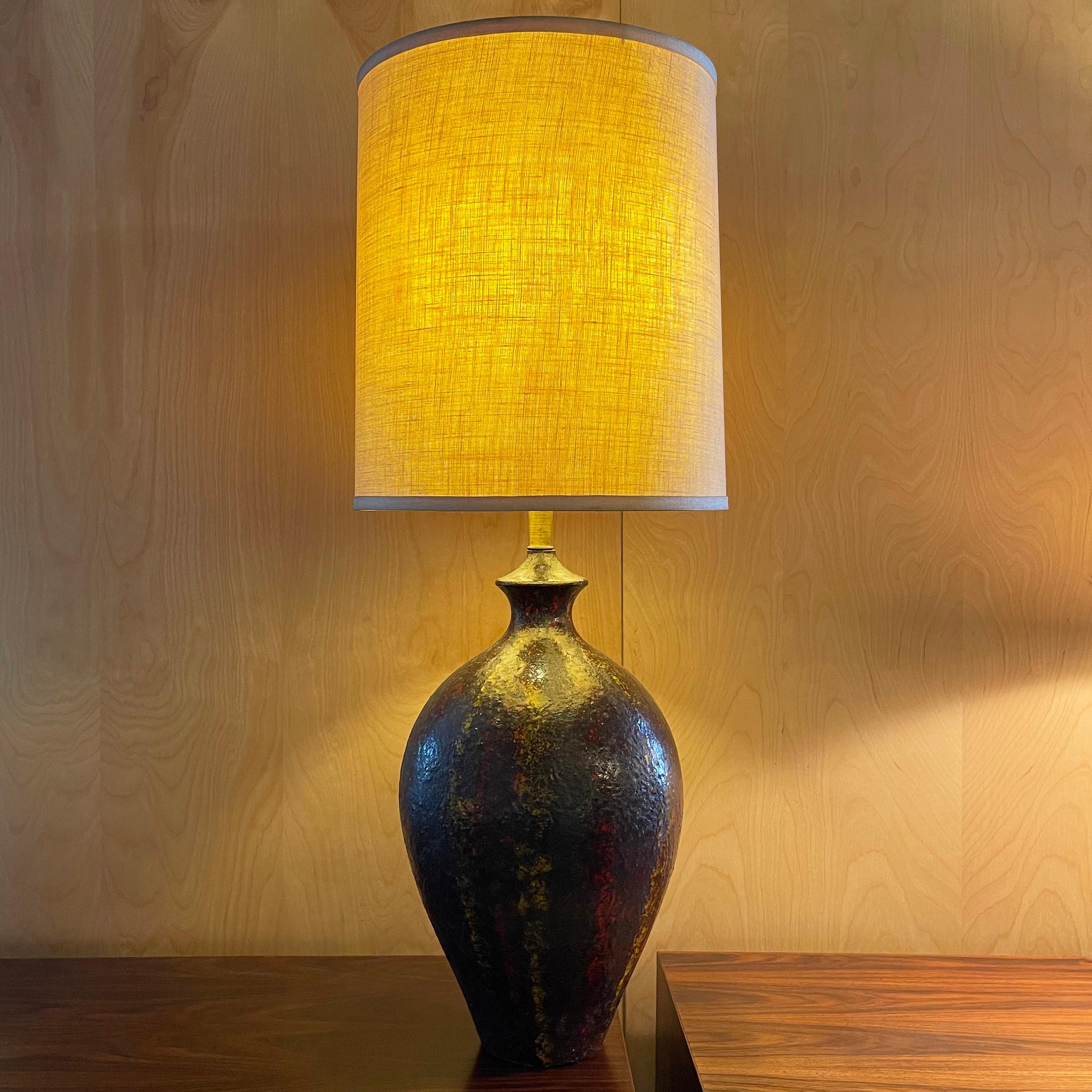 Large, Mid-Century Modern, table lamp features an urn shape, art pottery, Brutalist glaze base in shades of brown, yellow and red with brass neck. The vintage linen drum shade measures 15 inches diameter x 18 inches height. Overall height with shade