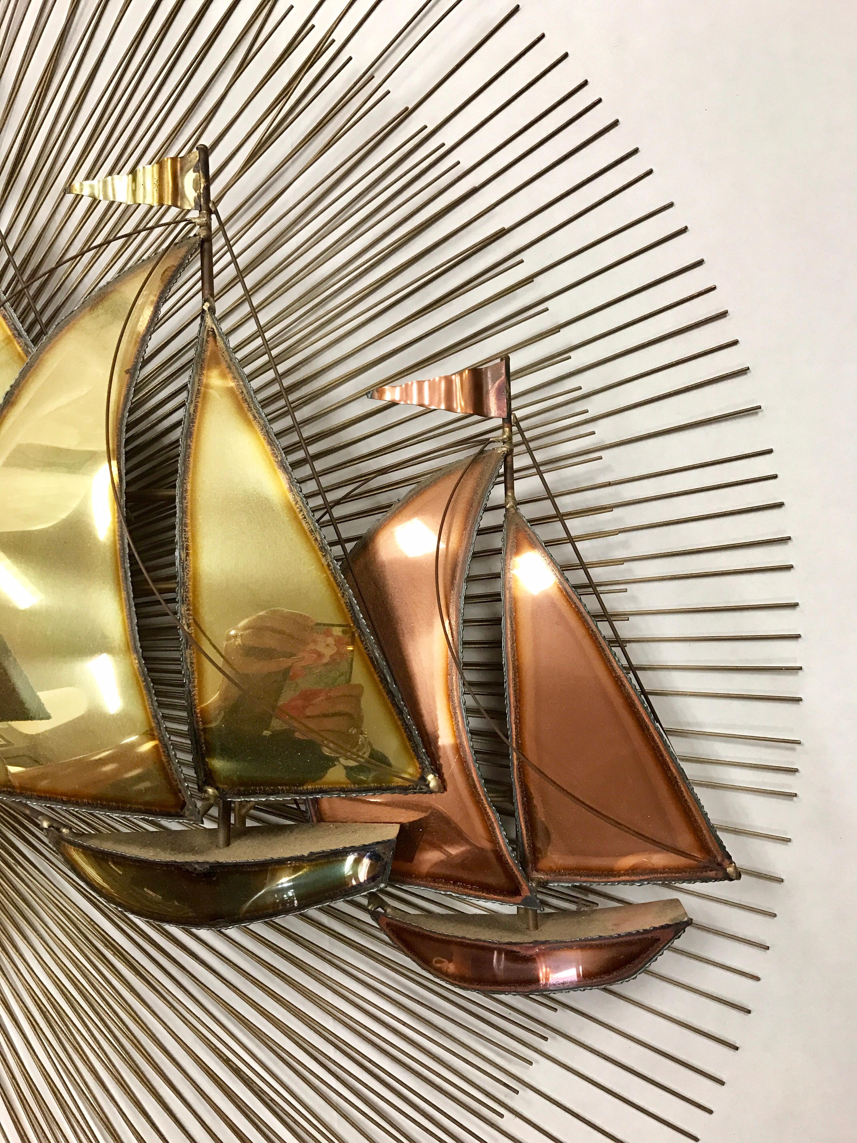 Mid century sunburst has two layers of brass spindles with alternating brass and copper sailboats. In the style of Curtis Jere.