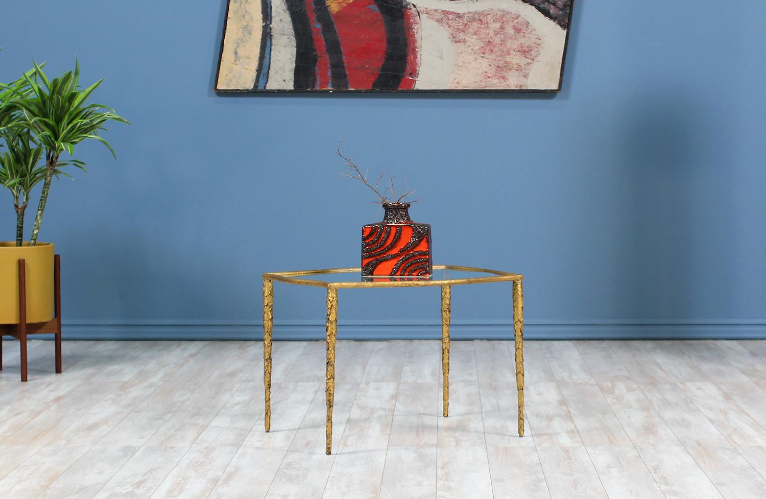 Mid Century Brutalist side table designed and manufactured in the United States circa 1960’s. This beautiful side table features a gilded metal structure in the fascinating brutalist style that supports the new custom glass top. The brass-toned