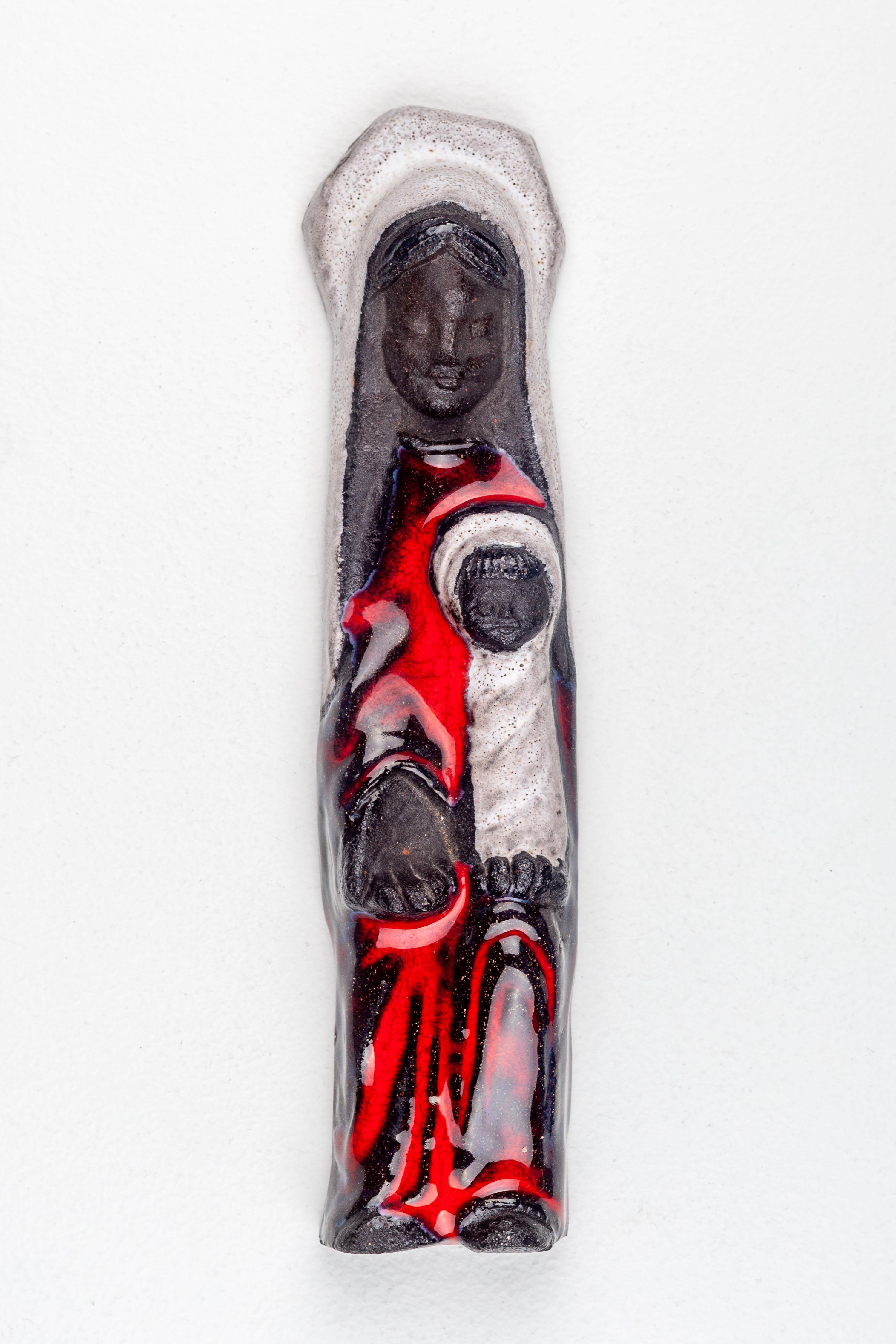 Midcentury Brutalist Depiction of the Virgin Mary and Child Jesus, Handcrafted in European Studio Pottery. In this depiction, the Virgin Mary is represented as a smiling figure in black, adorned with a glossy red robe. Meanwhile, the Child Jesus is