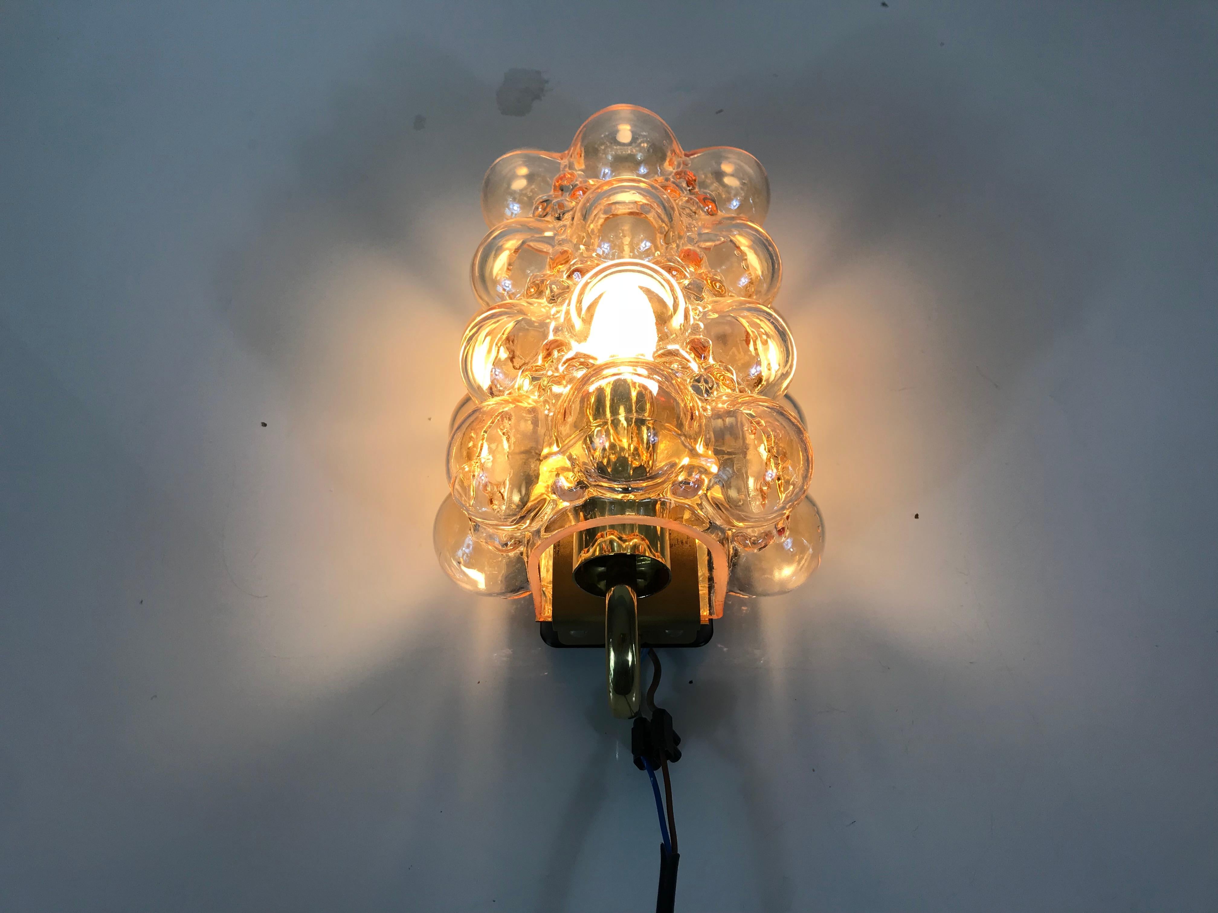 A midcentury wall lamp by Glashütte Limburg made in the 1960s. It was designed by Helena Tynell who is famous for the bubble shape. Amber bubble glass shade with brass bottom.

The light requires one E27 light bulb.