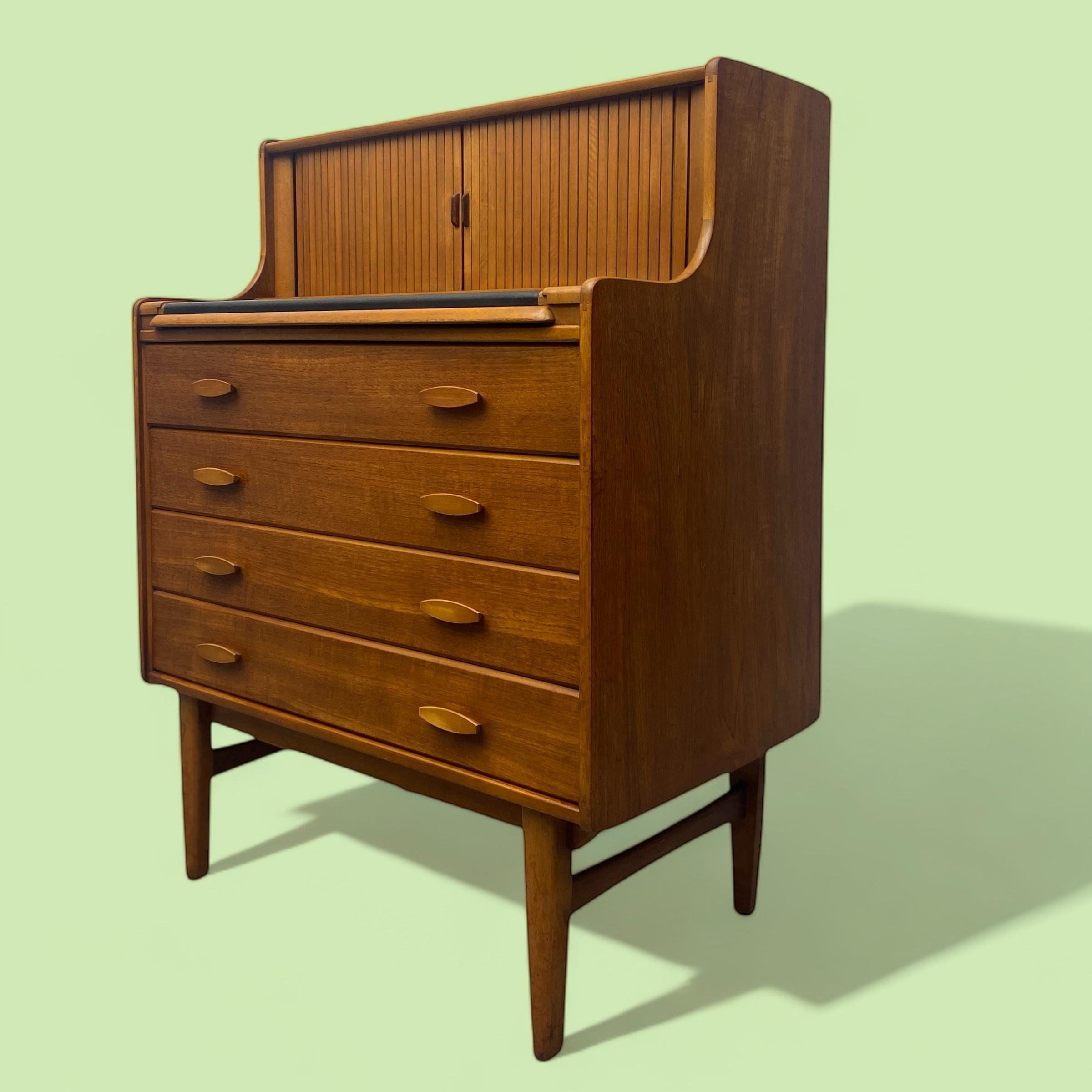 A superb & rare 1960s bureau in teak by English Welters of Wycombe. This delightful desk has two tambour doors revealing stationary pigeon holes, a pull out writing surface in black leather, four drawers & sits on elegant midcentury style legs. A