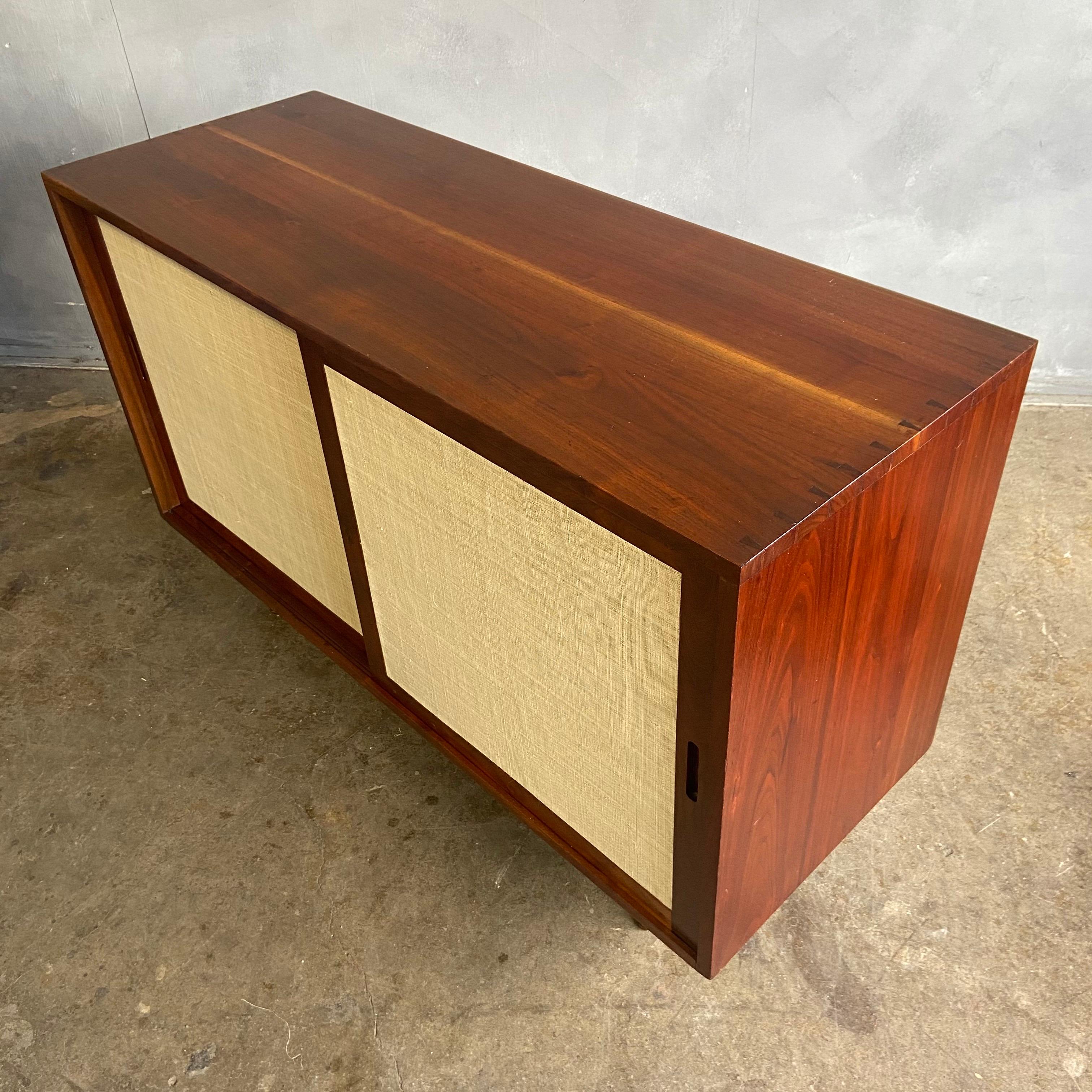 For your consideration is this lovely Phillip Lloyd Powell sliding door cabinet with perfect proportions. Featuring black walnut with his signature dove-tail joinery and leg dowel connections. inside cabinet has two adjustable shelves on the right