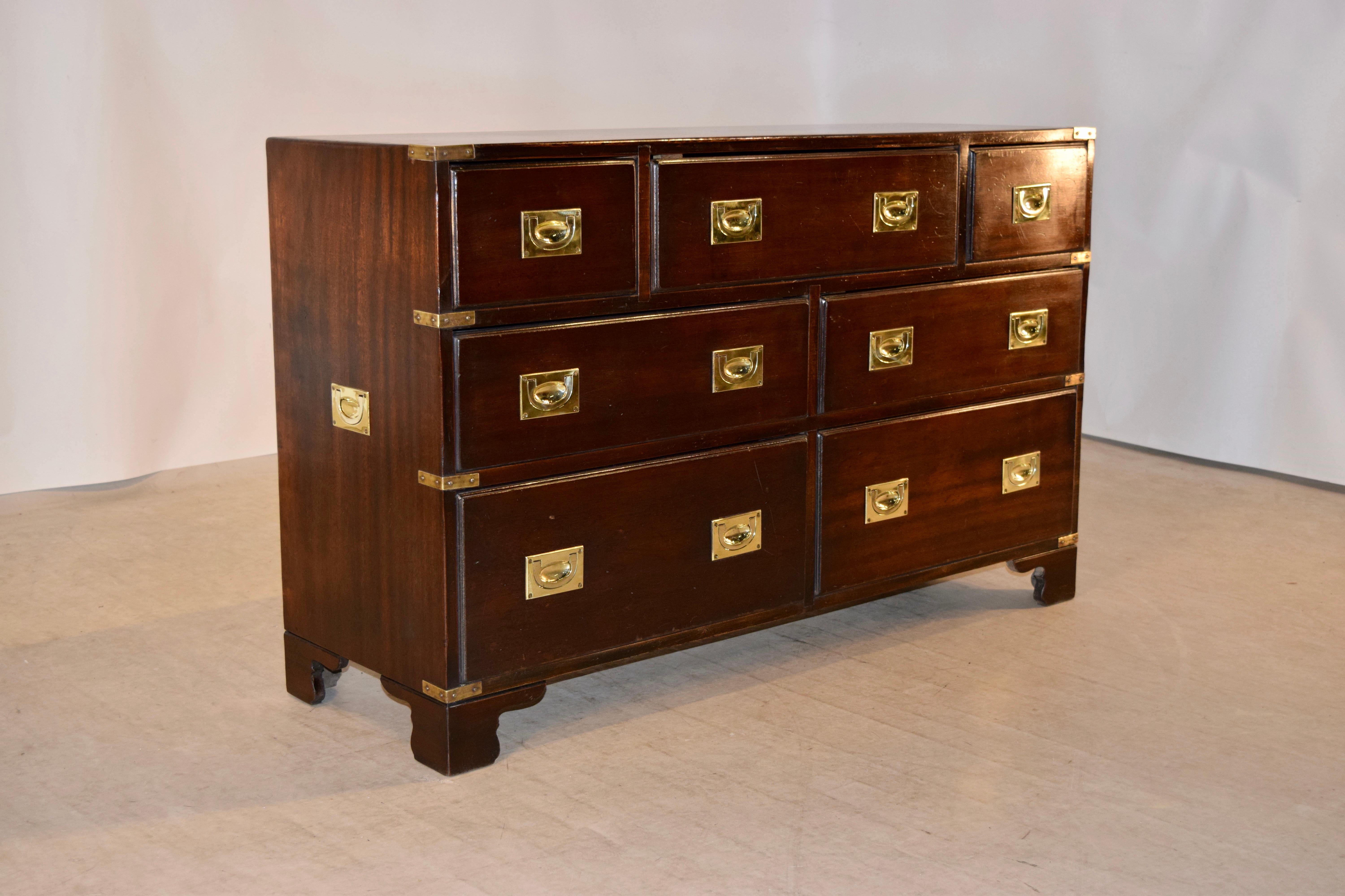 Midcentury English Campaign style chest made from mahogany. The top has lovely figuring and is banded with brass corners. The case contains a single larger drawer flanked by two smaller ones over two sets of two drawers, all with lovely brass