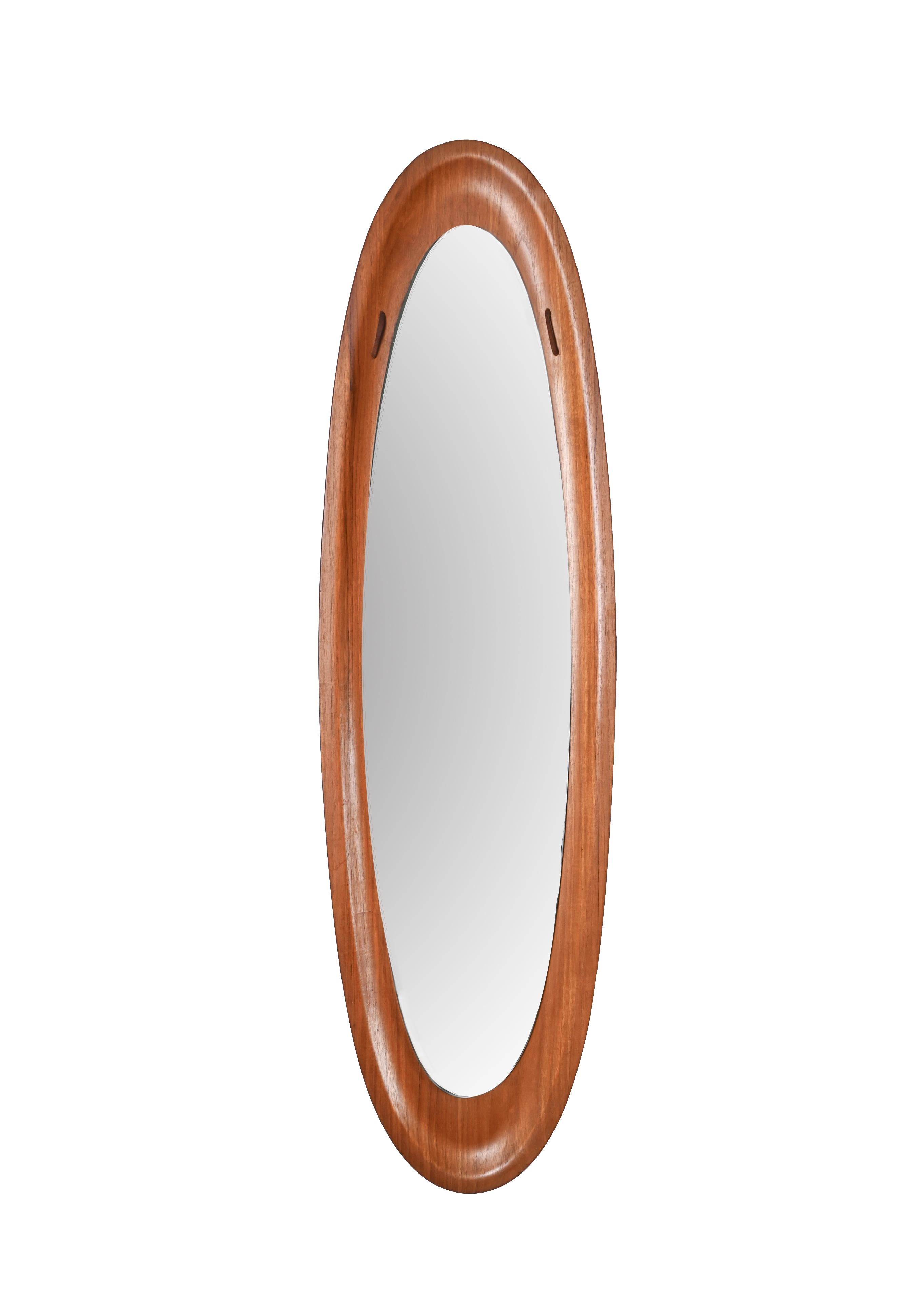 Amazing midcentury teak wood elliptical wall mirror. This fantastic piece was designed by Franco Campo and Carlo Graffi in Italy during the 1960s.

This wonderful piece features a curved teak wood frame with beautiful wood grains that holds an