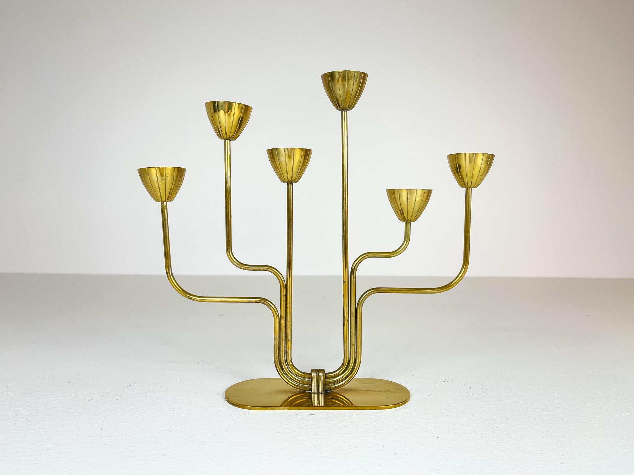 This brass candelabra was made in 1960s at Ystad Metall in Sweden. Designed by Gunnar Ander. Nice lined brass with holders for small candlesticks.

Good condition with wear of age. 

Measures: H 26cm, W 27 cm.
 