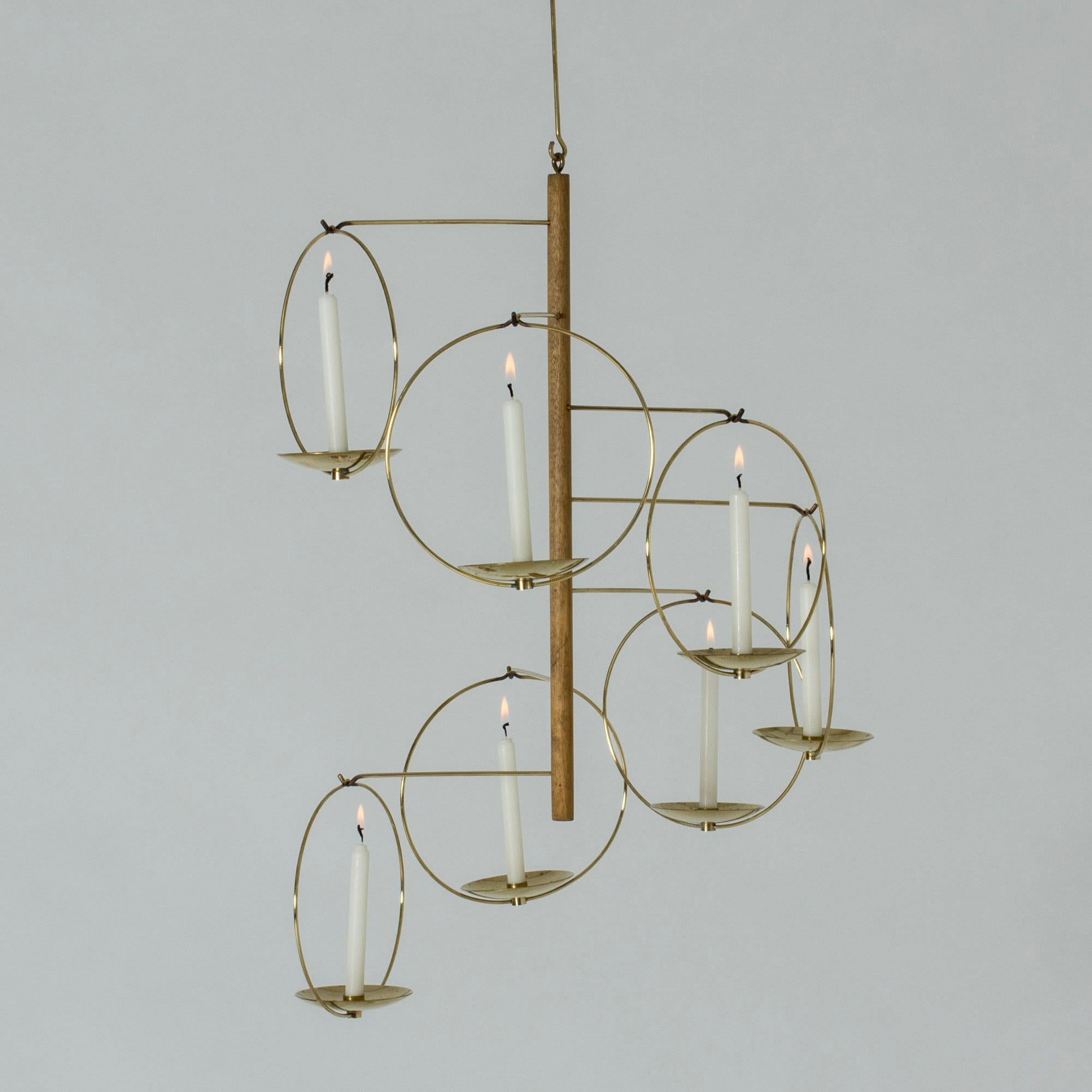 Beautiful, light and graphic candle chandelier from Aarikka. In the middle is a teak pole from which brass slender brass arms are extended, each holding a candleholder. Fits thin candles.

The height is 98 cm including the brass suspension pole,