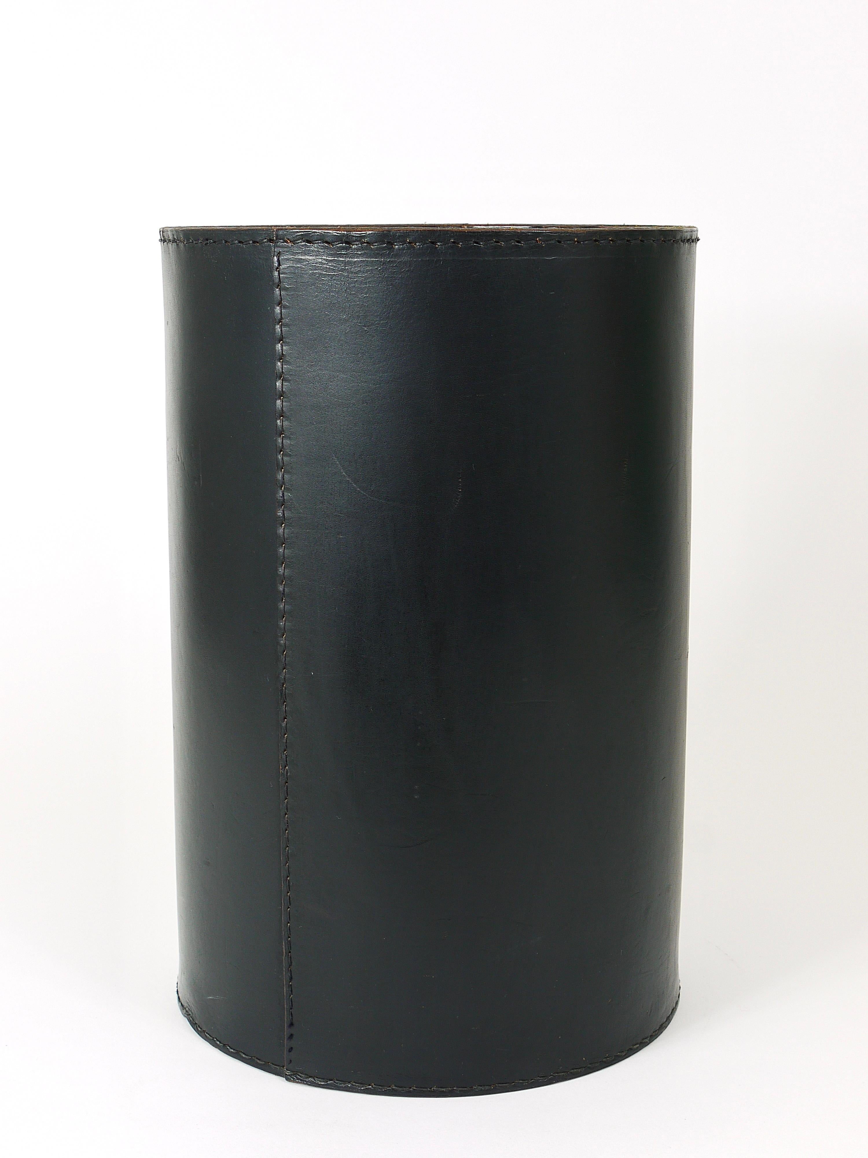 A beautiful cylindric Mid-Century Modern wastepaper basket from the 1950s, designed an executed by Carl Auböck, Vienna. Made of black leather. In good condition, with normal signs of age and charming patina.