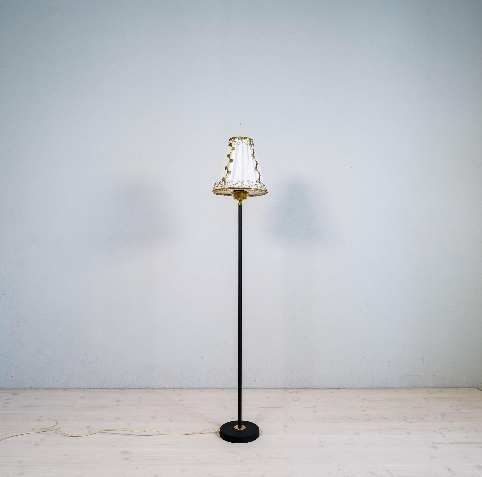 Minimalistic floor lamp Designed by Eric Wärnå in Sweden during the 1960s. This lamp features a cast iron base with brass details. The shade is made in cotton and with wonderful small parts in brass to give a great impression of that 50-60s Swedish