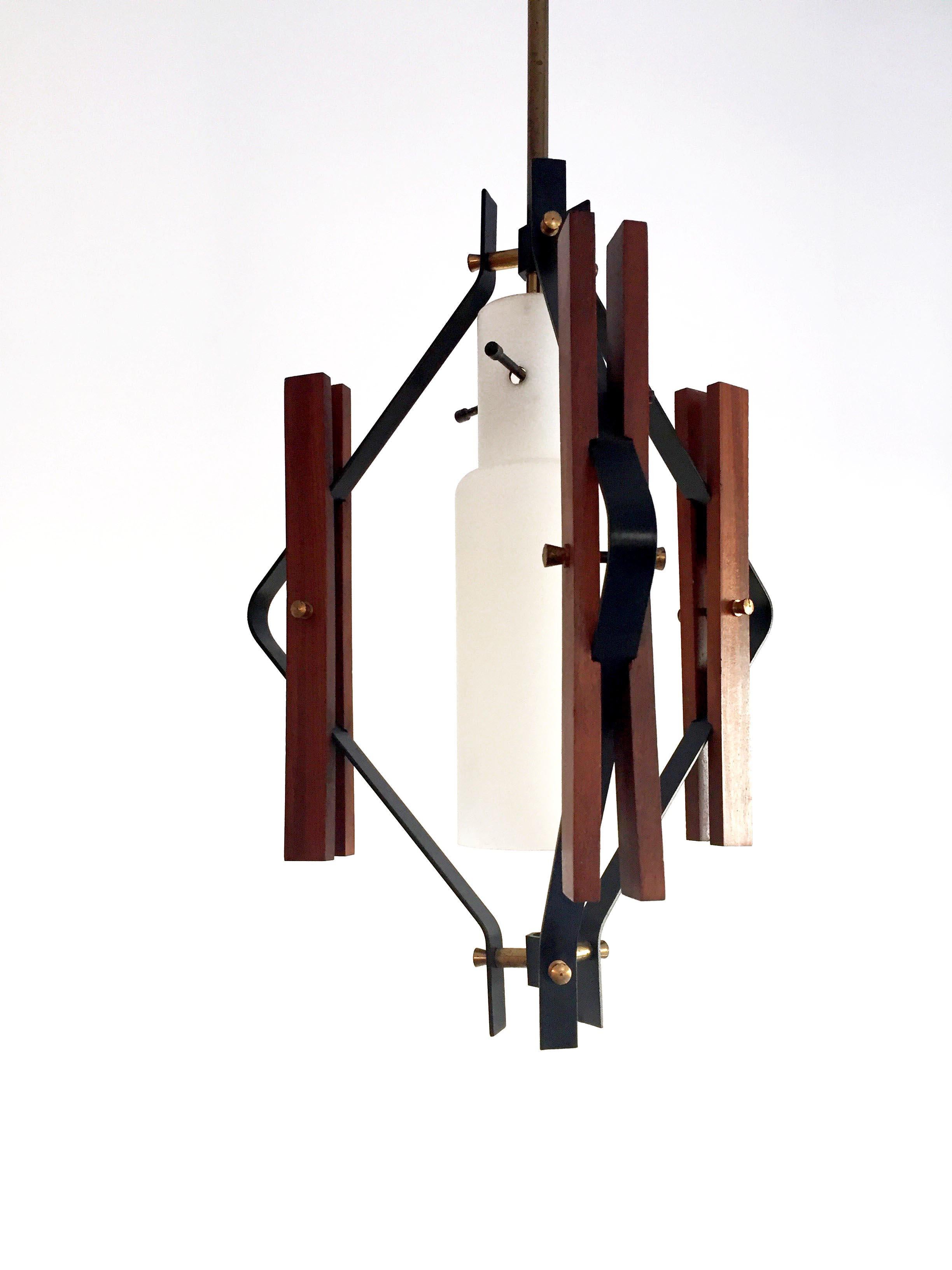 Amazing ceiling lamp in teak wood profiles with a beautiful structure made with black painted Iron.
All details are in polished brass.
The lamp presents one cylindrical opaline glass in the middle.
The stem to fix the lamp to the ceiling is in