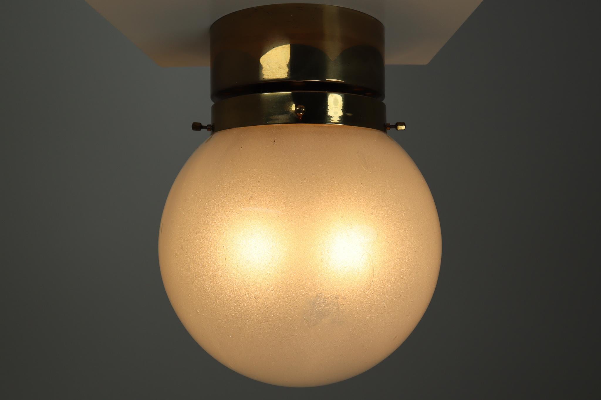 Midcentury hotel ceiling or floor lights with brass frame and large hand blown white frosted glass globes. The lights are beautifully thanks to the hand blown glass. The pleasant light it spreads is very atmospheric, these lights will contribute to