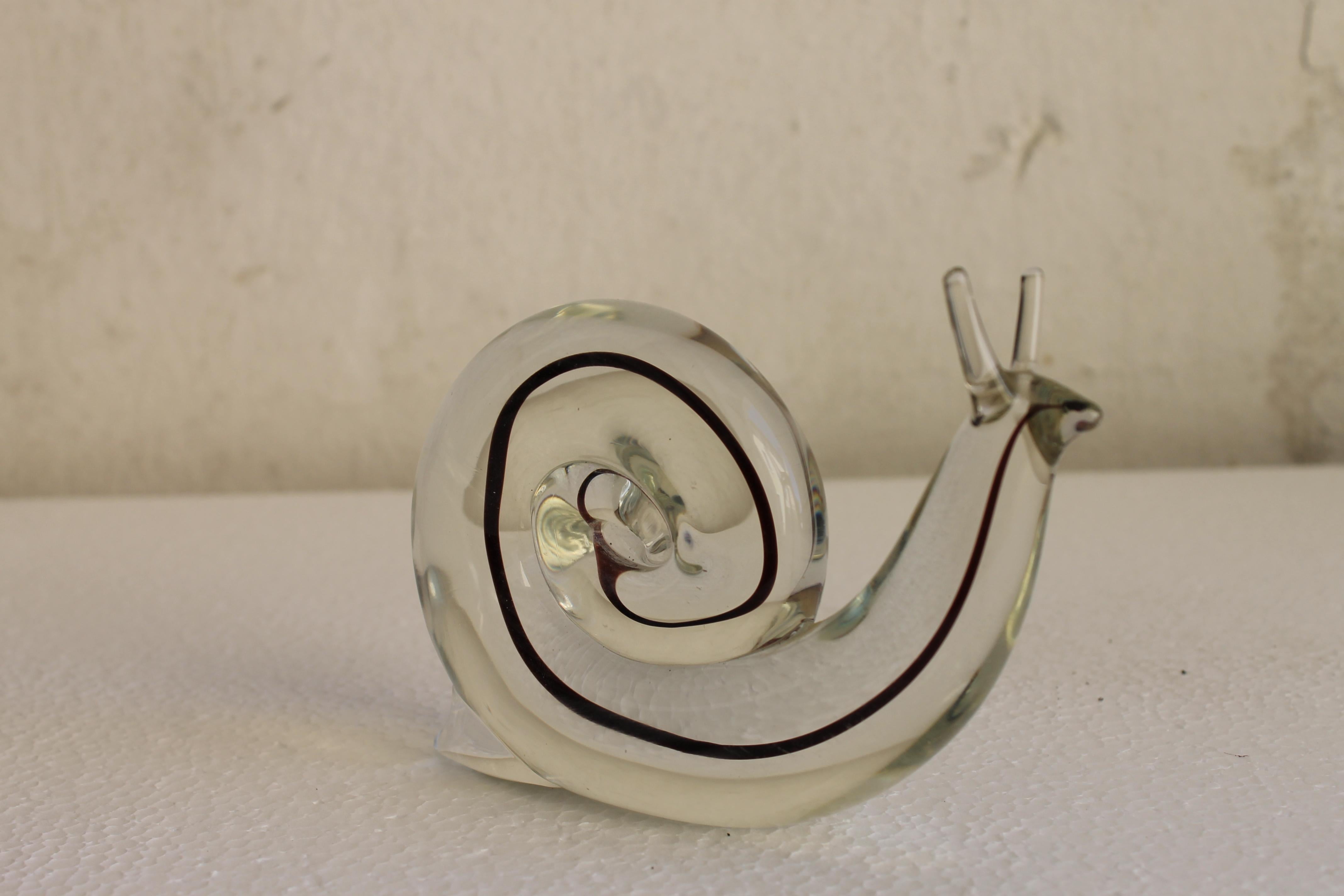 Mid Century CENEDESE Snail sculpture paperweight Sommerso Murano clear Glass, Italy '70s.

A beautiful piece made of thick clear Murano glass.This elegant snail has a black-purple filament running within. The light passing through this sculpture