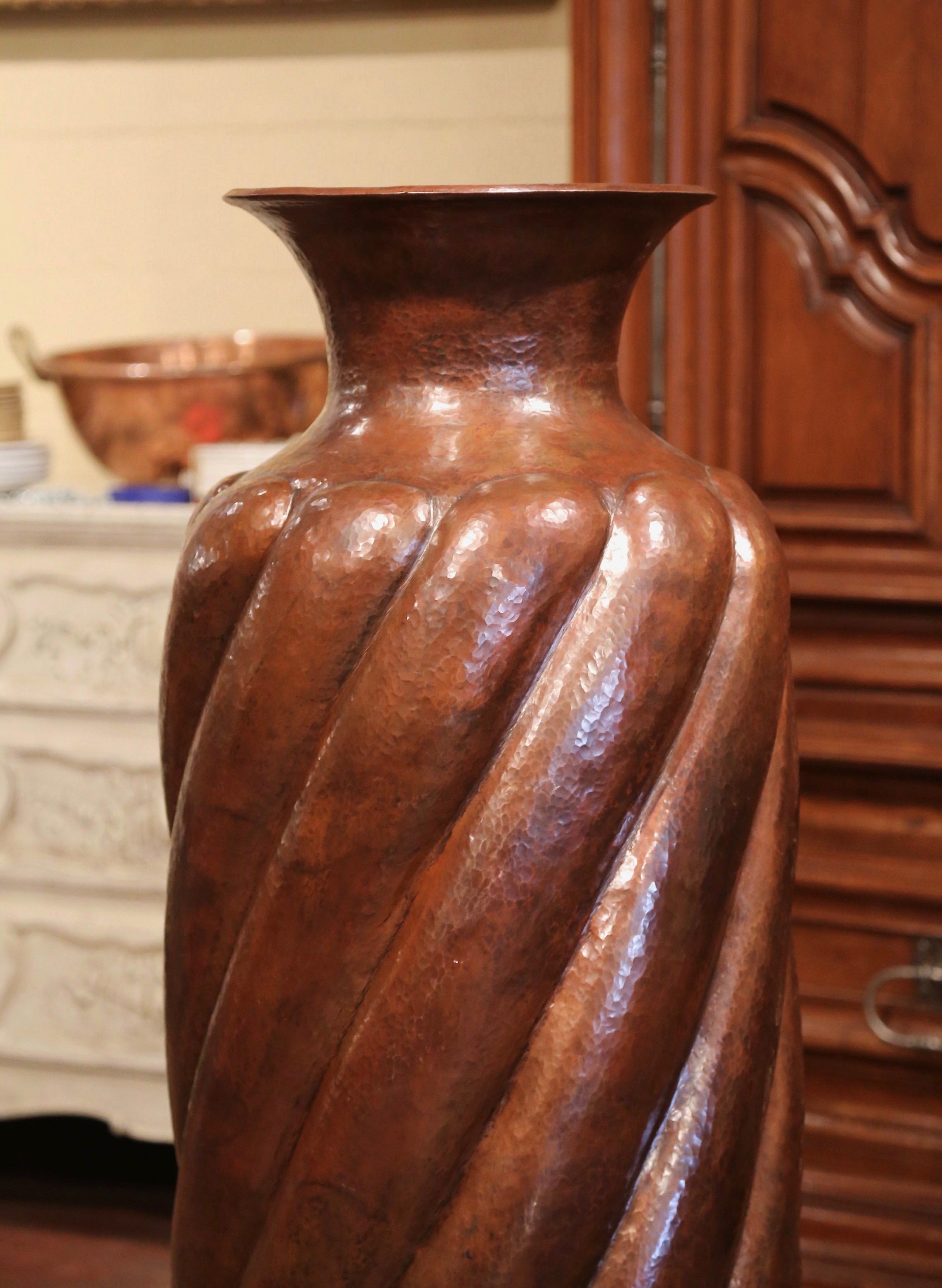 Place this tall and elegant vase in an entry or a room corner. Crafted in Mexico circa 1950, the large copper vase with tapered body and wide neck is hammered and embellished with repousse twisted stripe decor. The decorative vase is in excellent