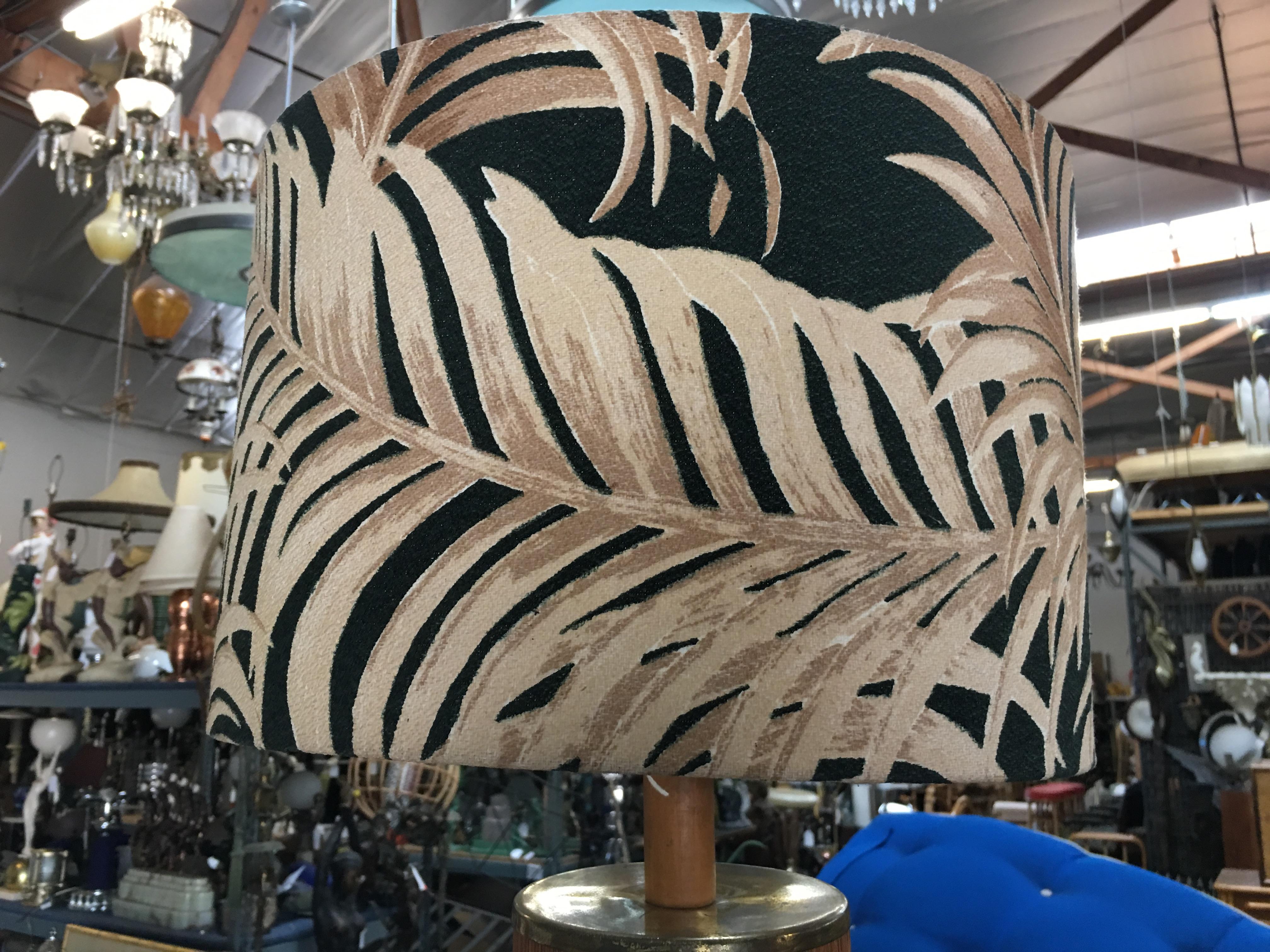 Midcentury Tropical lamp featuring a light stained oak base wrapped in decorative strung Bamboo with a top brass cap. The lamp comes with its original Fabric Palm Leaf Shade by Spectrum fabrics.