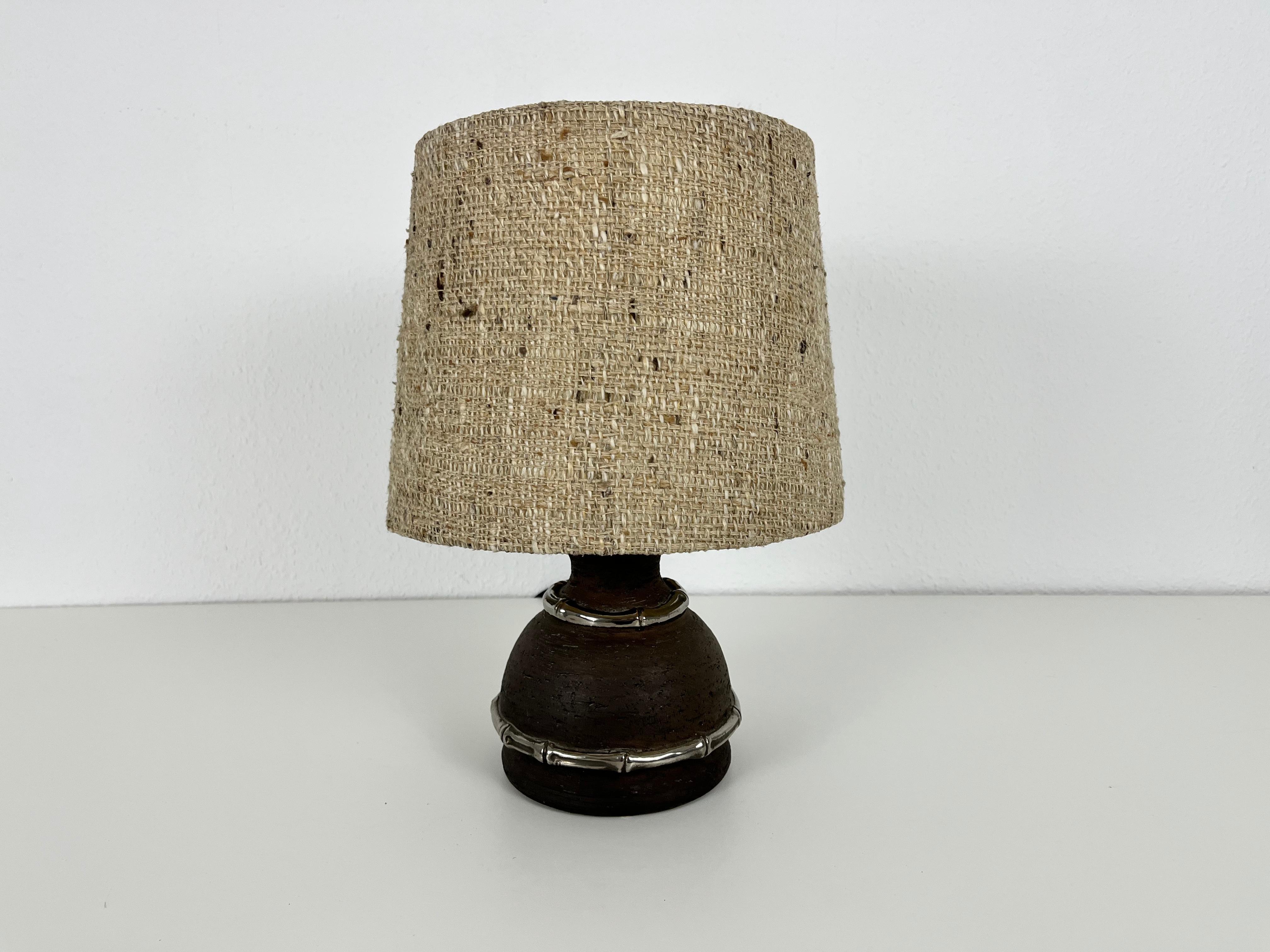Eine schöne große Tischlampe aus den 1960er Jahren. Der Sockel ist aus brauner Keramik gefertigt. Der Lampenschirm hat eine beige Farbe. Die Tischlampe hat ein schönes italienisches Design.

Die Leuchte benötigt eine E27-Glühbirne. Guter