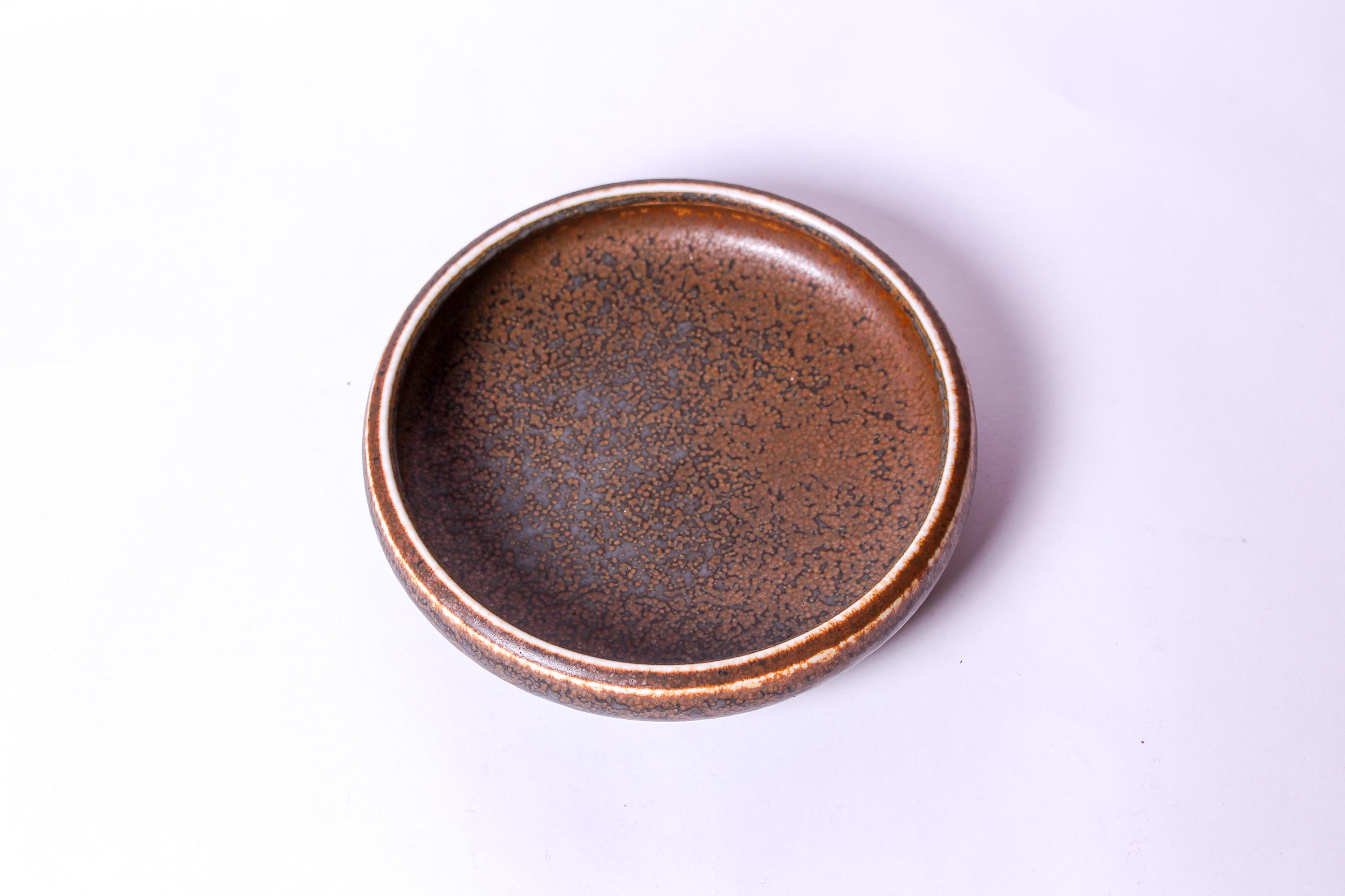 A midcentury ceramic bowl designed by Swedish designer Carl-Harry Stålhane. The bowl is of a large model with beautiful glaze. Its in very good vintage condition with small signs of usage consistent with age. Marked with both manufacture stamp by