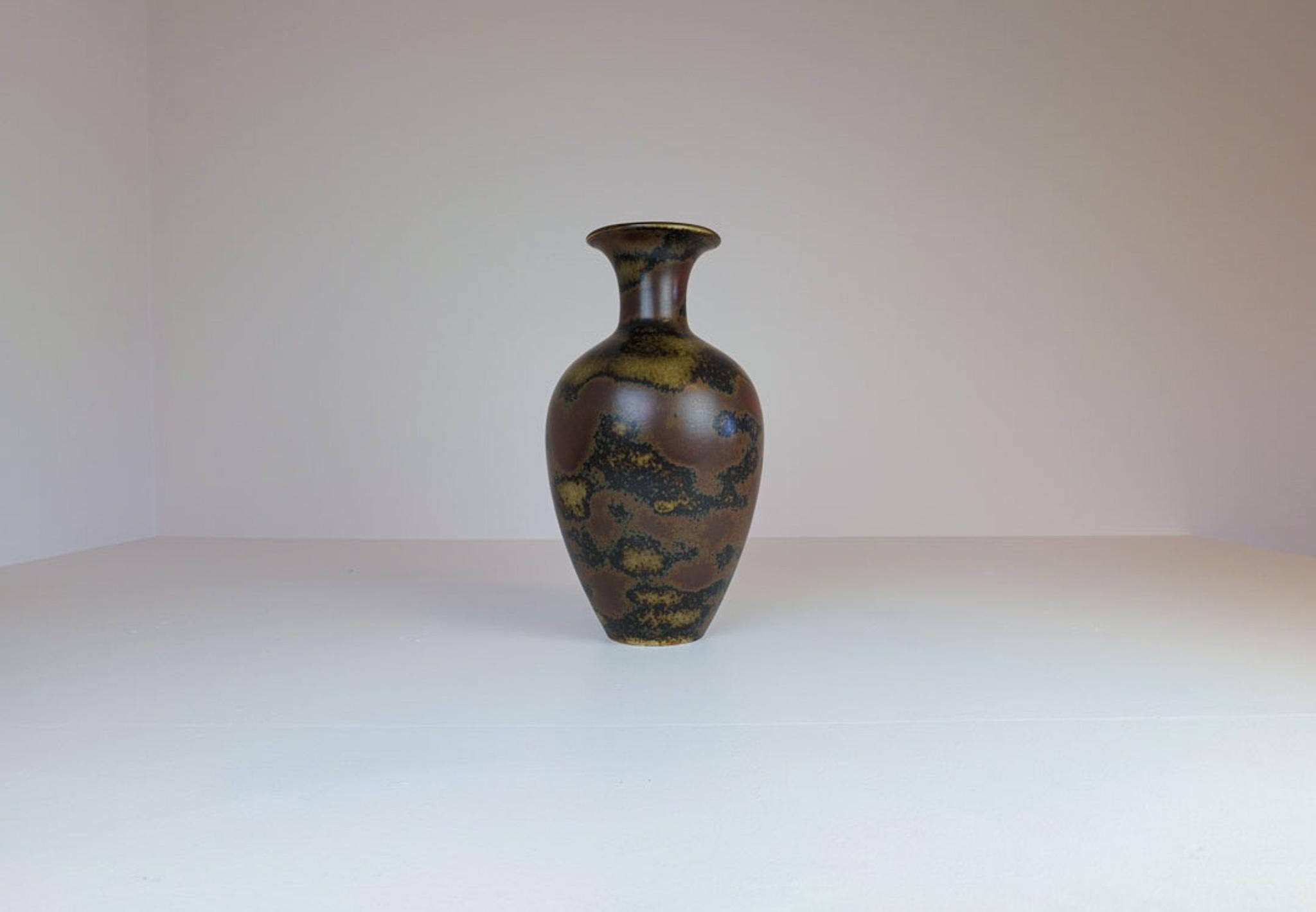 A gorgeous floor vase produced at Rörstrand and designed by maker/Designer Gunnar Nylund. Made in Sweden in the midcentury. Beautiful brown glazed in shifting dark camouflage colors. Rare seen item with this color. 

Good vintage