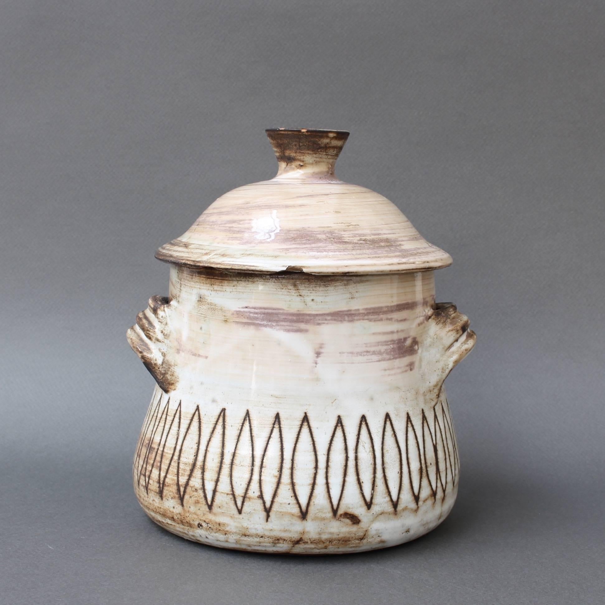 Midcentury decorative ceramic jar, circa 1960s by Jacques Pouchain, Atelier Dieulefit. This decorative jar with lid was created in Pouchain's trademark tones of brown with white and beige glaze. The two handles are brushed in brown and below,