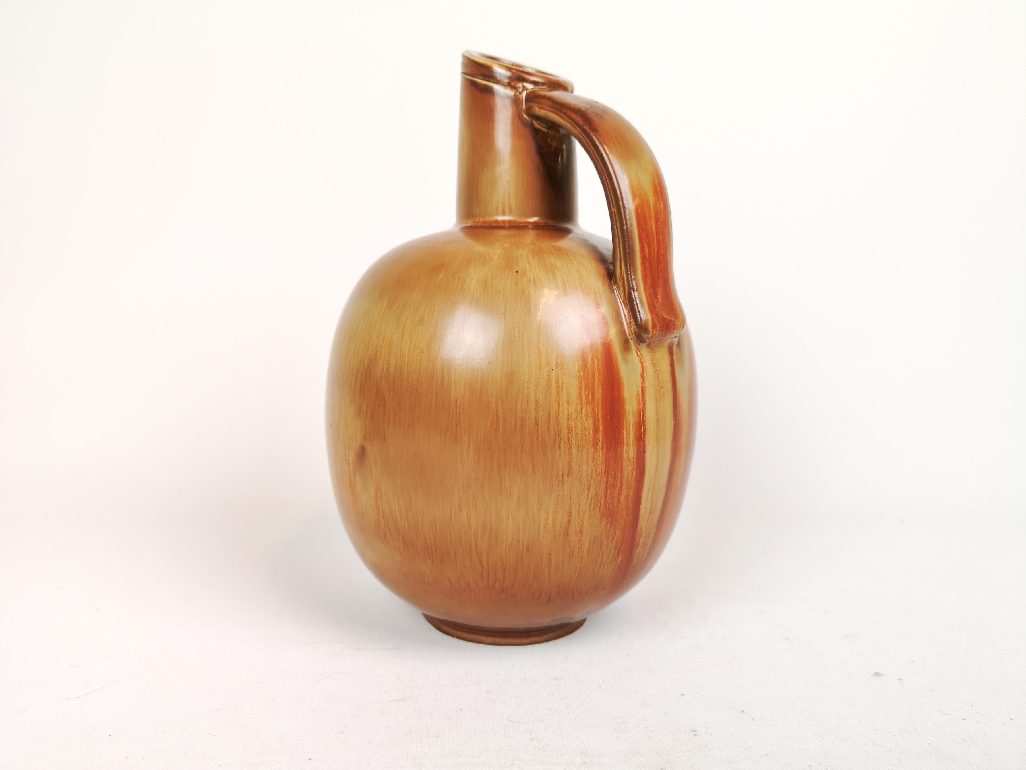 Ce merveilleux vase a été créé et dessiné par Gunnar Nylund à l'usine de Rörstrand dans les années 1950, en Suède.

La glaçure brune et dorée est étonnante et s'harmonise parfaitement avec la forme du vase. 

Très bon état. 

Mesures : H 23