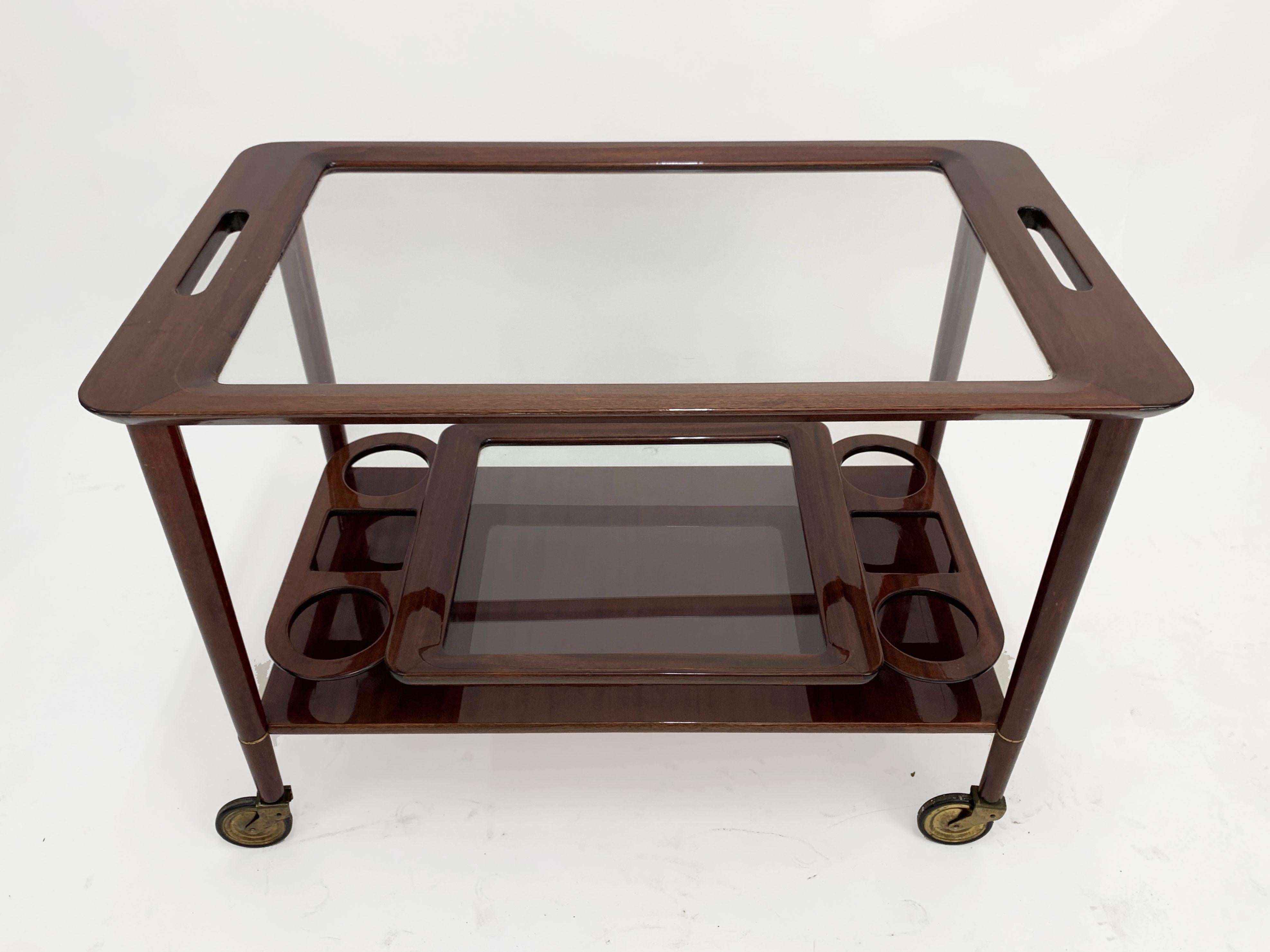 Fantastic midcentury wood bar cart with glass serving trays. This piece is attributed to Cesare Lacca and it was designed in Italy during 1950s.

This wonderful piece comes with a removable glass tray and has an ergonomic bottle holder, while the