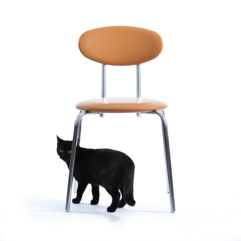 This elegant mid-century modern chair was produced by Kovona in the 1970s and features a distinctive bent tubular chrome frame paired with its original beige leatherette seat and backrest. The minimalist design highlights clean lines, functional