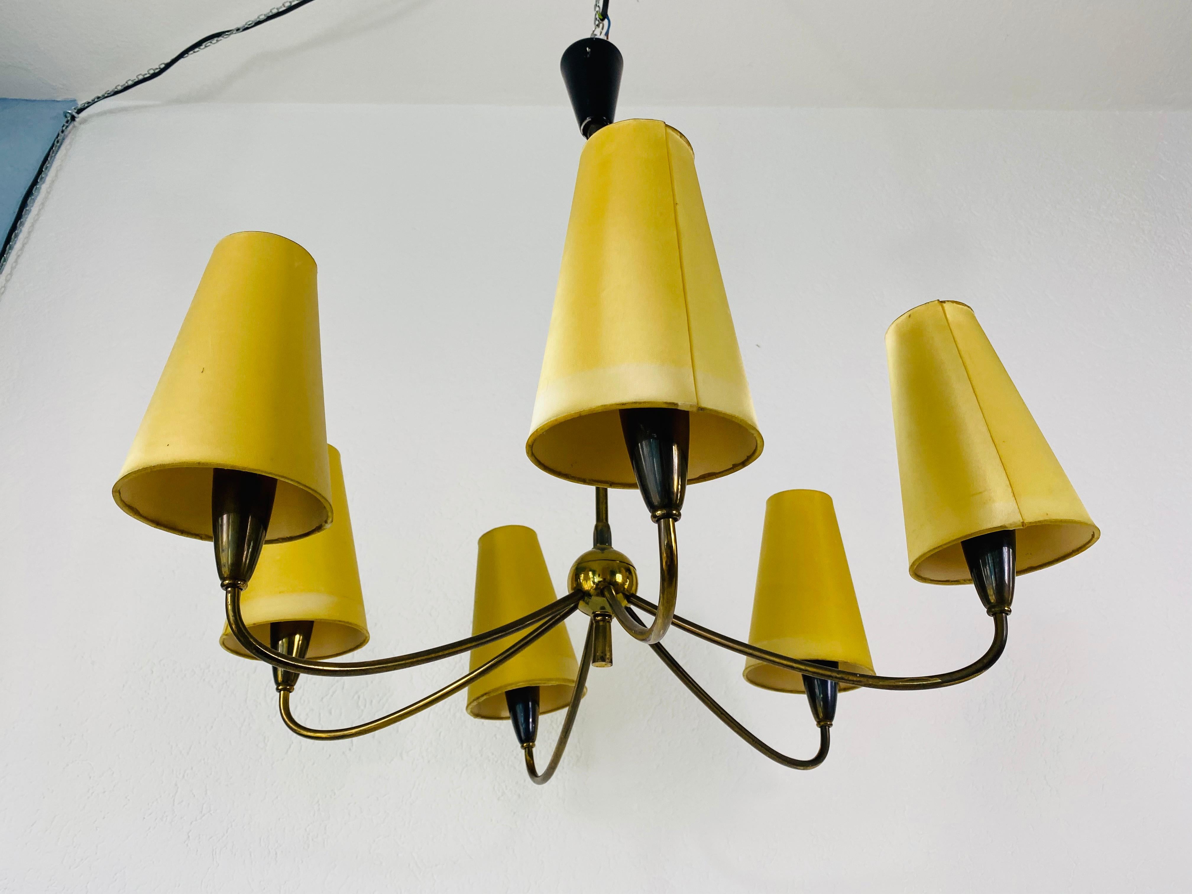 Midcentury chandelier by Maison Lunel made in the 1950s. The light has six cloth shades in a beige colour. They are fixed onto the light bulbs. The body of the lamp is made of brass. 

The light requires six E14 light bulbs.