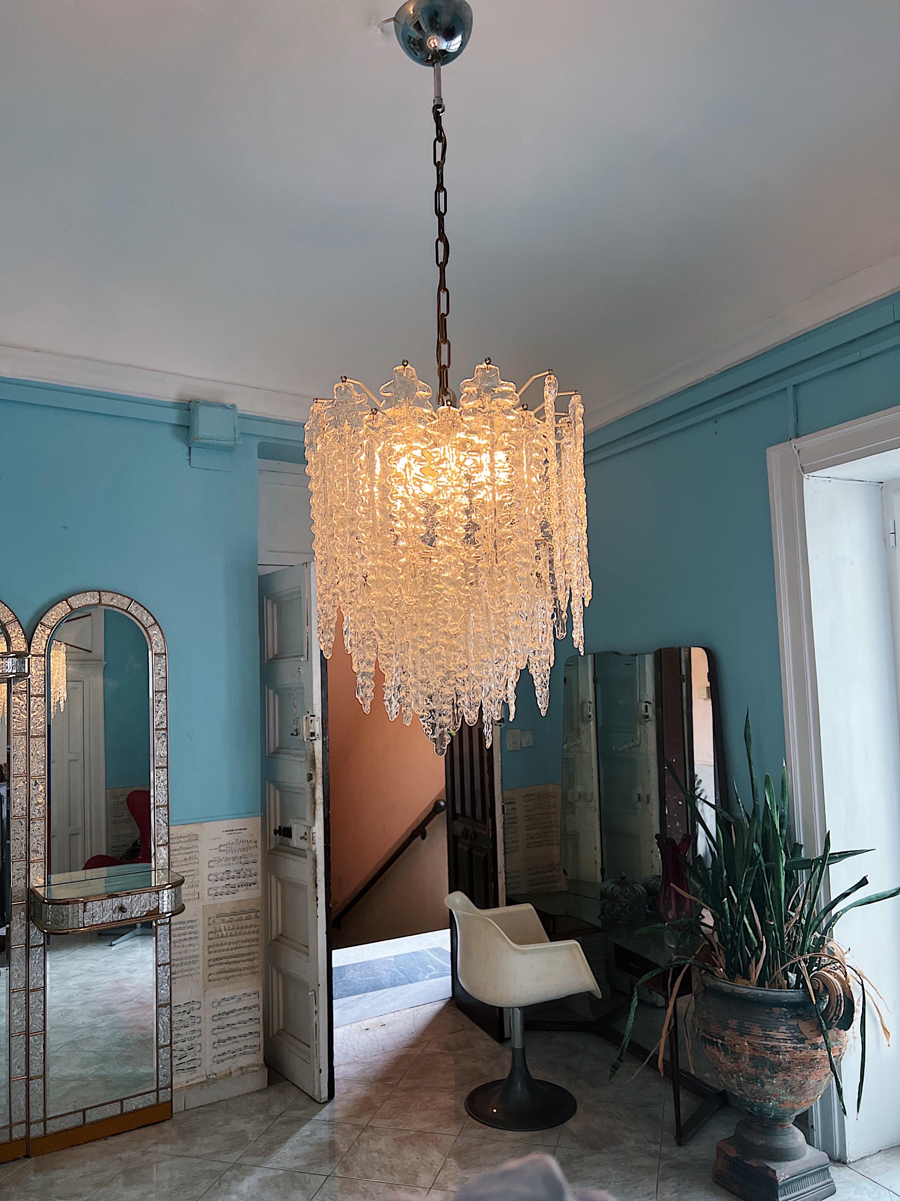Una belleza intemporal del cristal de Murano. Esta opulenta lámpara de araña, una obra maestra, fue artísticamente elaborada por Venini en 1960. Su grandeza se compone de 60 hojas de cristal de Murano meticulosamente elaboradas a mano, dispuestas
