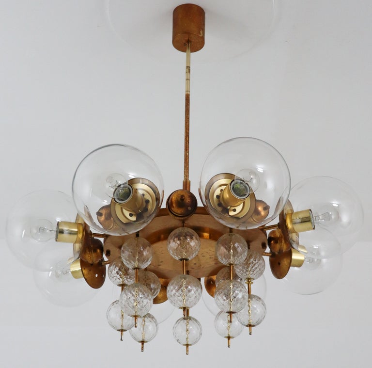 Midcentury chandelier with patinated brass fixture, Europe, 1950s

This patinated brass chandelier was produced in Europe in the 1950s. A spirited and chic design set chandeliers with brass fixture and hand blown glass. The chandelier with brass