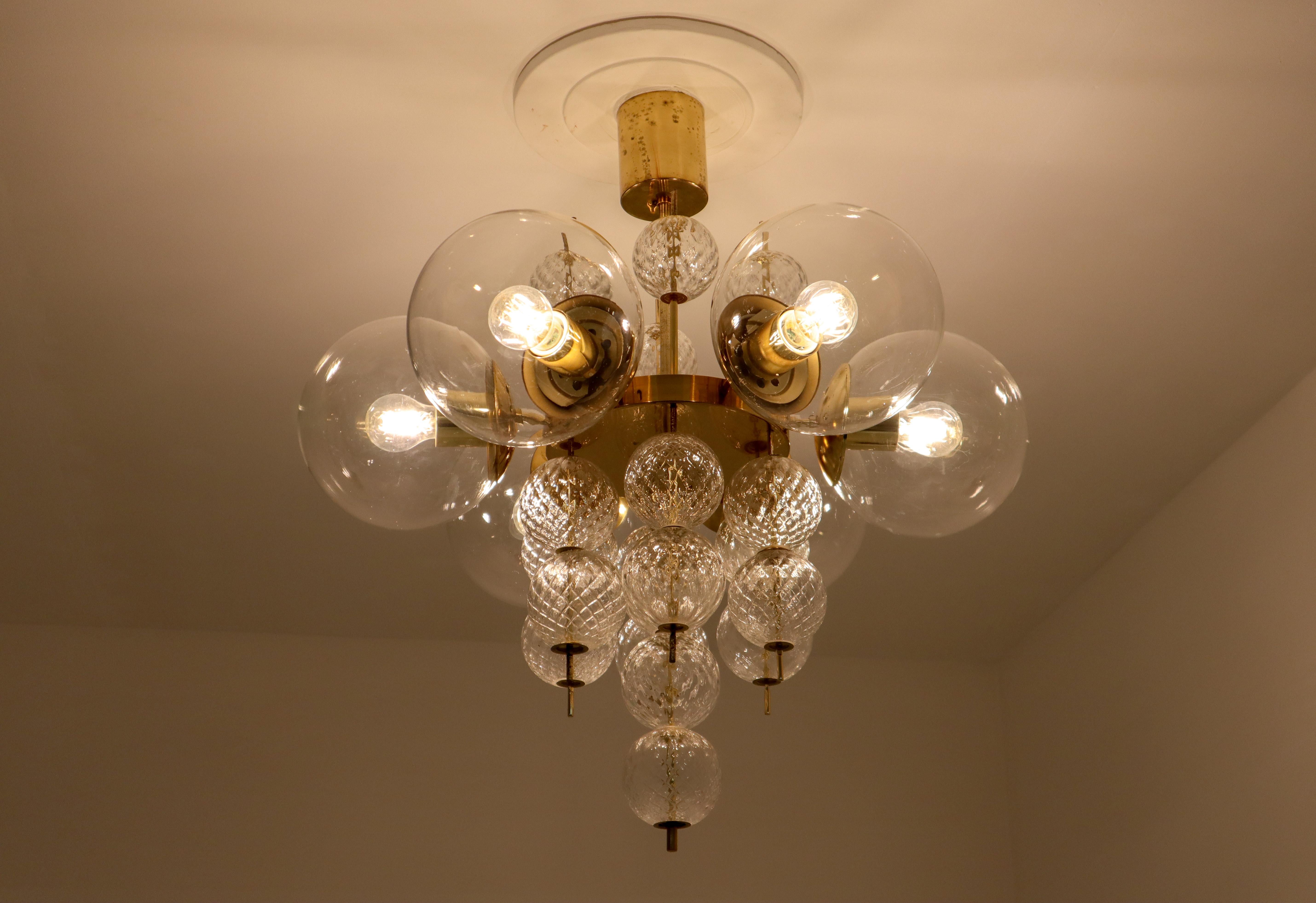 Large set brass chandeliers was produced in Europe in the 1970s. A spirited and chic design set chandeliers with brass fixture and handblown glass. The chandelier with brass frame consist of six lights, formed in a circle, with glass shades. The