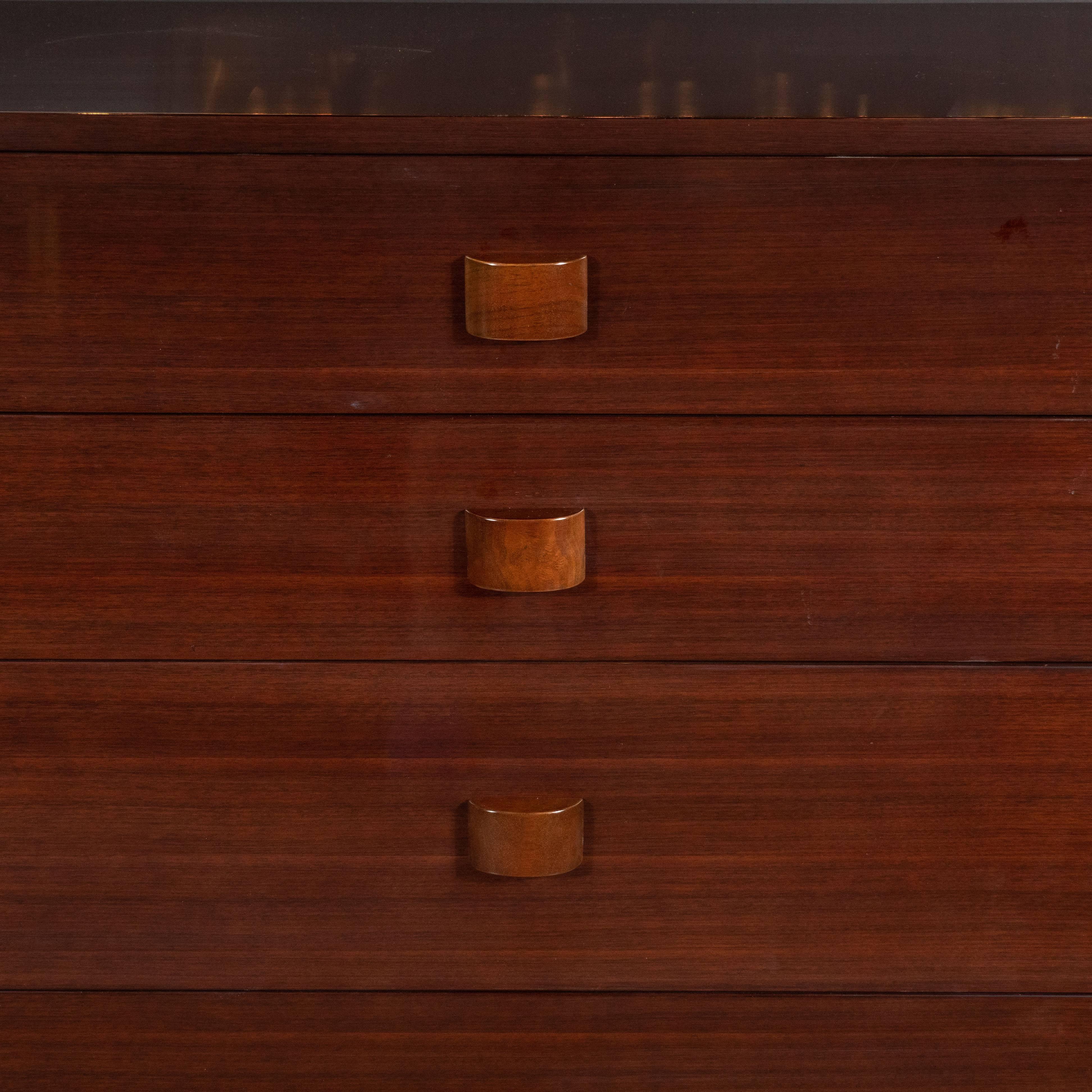 This refined and sophisticated high chest was realized by the fabled 20th century designer Gilbert Rohde for Herman Miller, circa 1942. It features a rectangular stepped skyscraper style base in ebonized walnut; and five drawers with streamlined