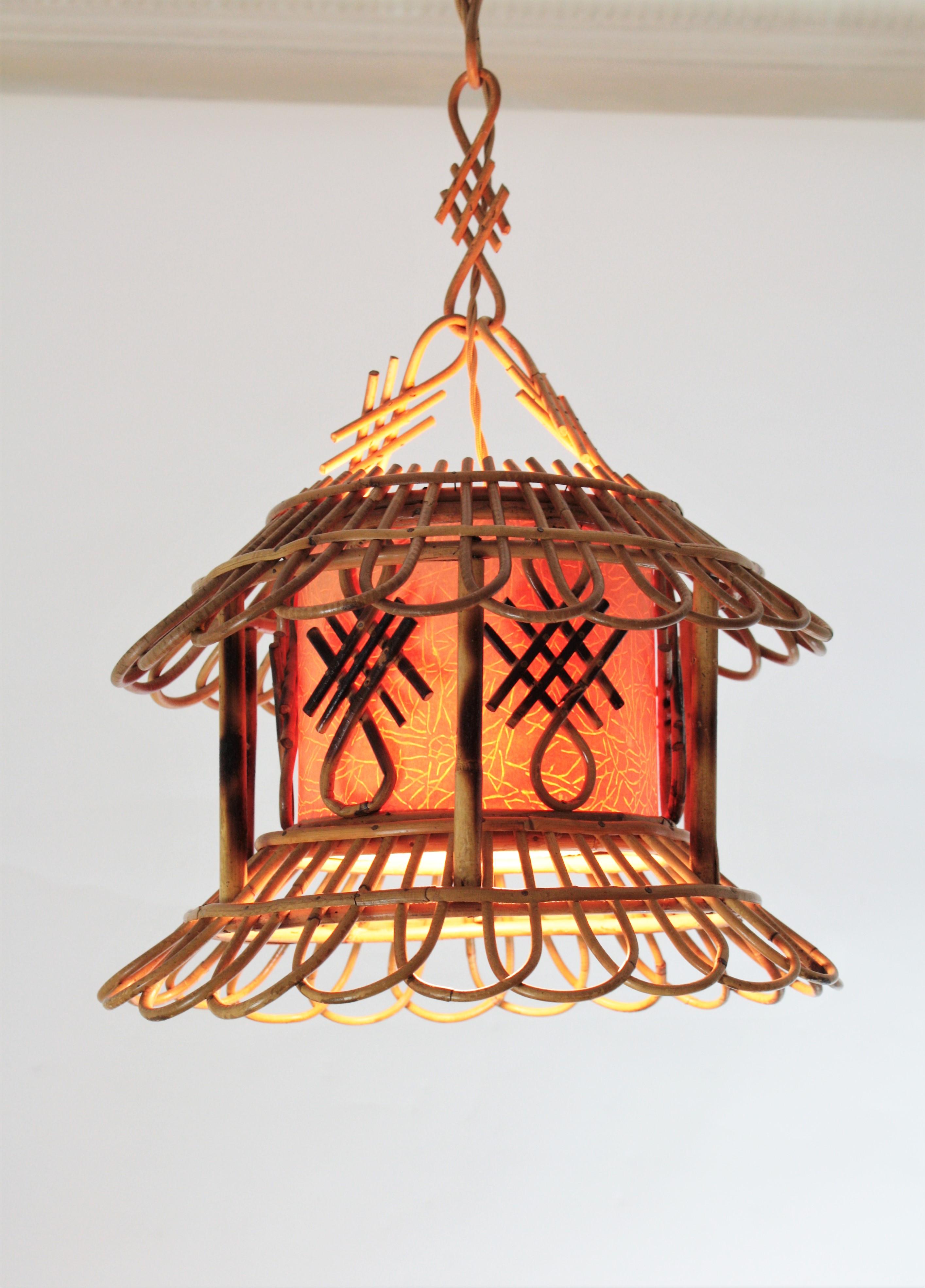 One of a kind chinoiserie style handcrafted bamboo and Rattan Pagoda shape pendant lamp with a paper shade, France, 1950s.
This rattan chandelier features a pagoda shape rattan hanging lamp with an interior paper shade. It hangs from a chain made of