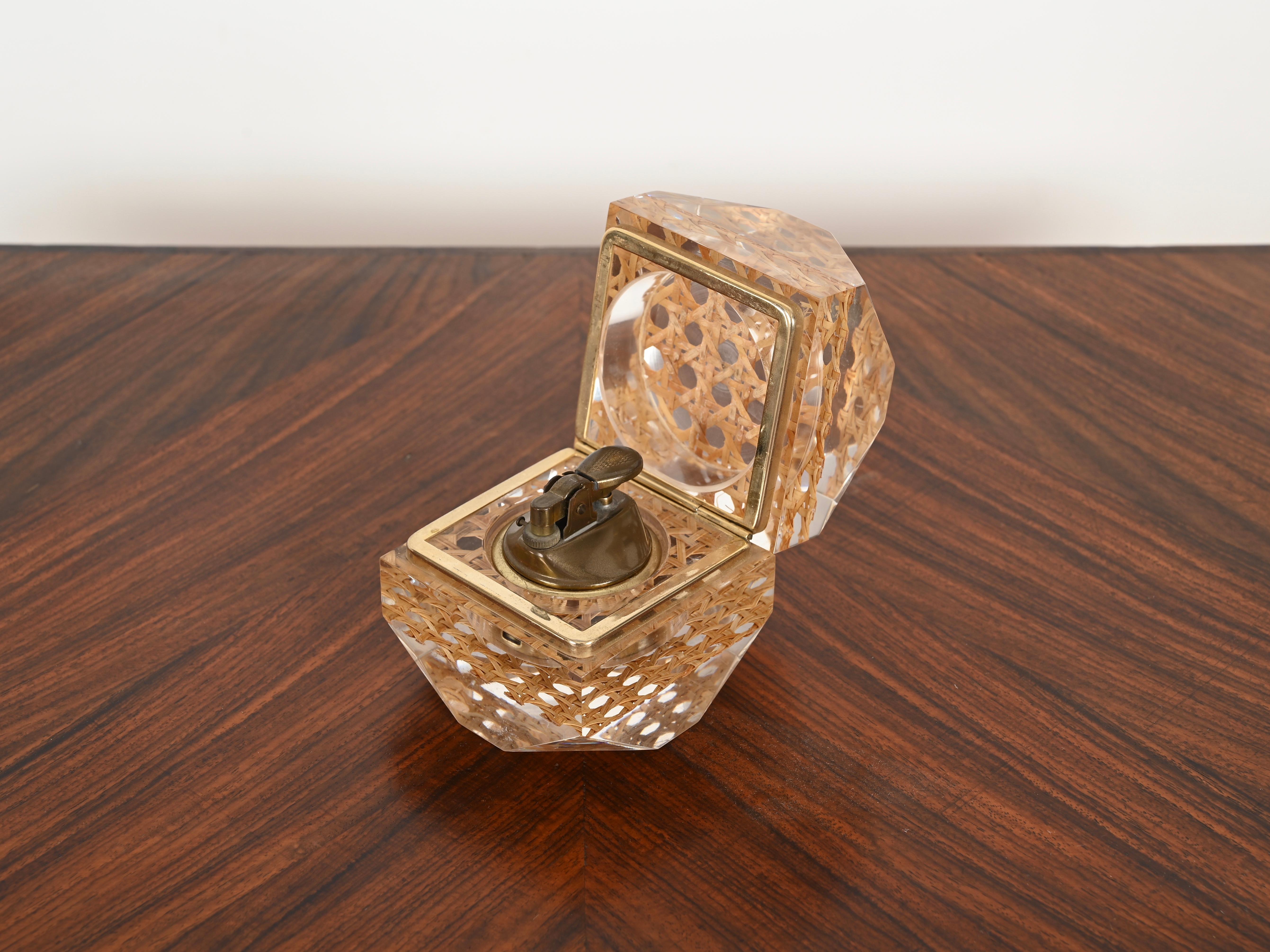 Stunning Mid-Century table lighter made in clear lucite, brass and Vienna straw. This delightful lighter is attributed to a Dior Home production and was made in Italy during the 1970s.

This octagon shaped lighter is spectacular thanks to the