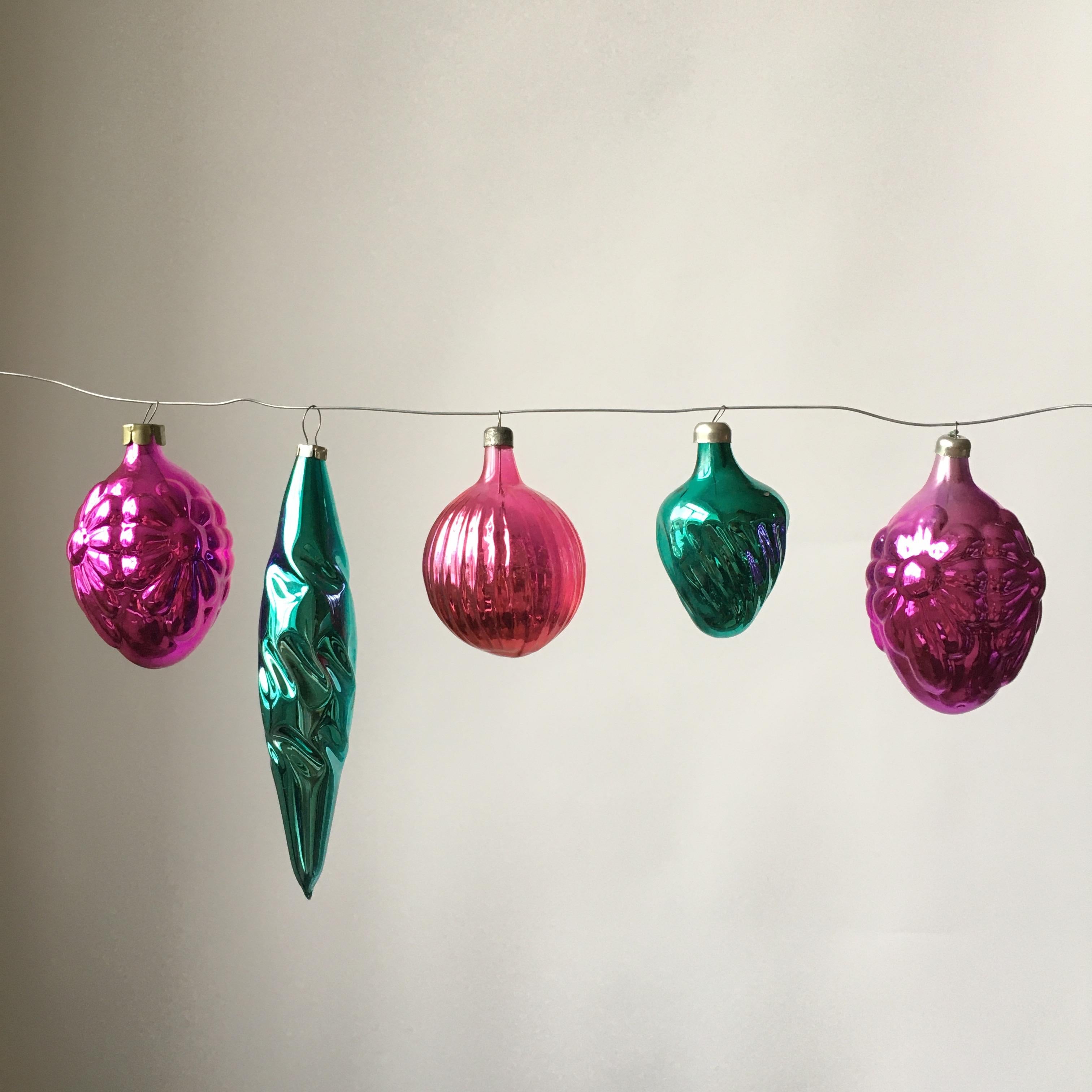 A mix of blown and formed glass Christmas toys of different styles. There is beautiful light reflection due to the half-transparent cover technique. Thin glass, some ornaments feature cracks under the metal cup, but it's not visible. Beautiful