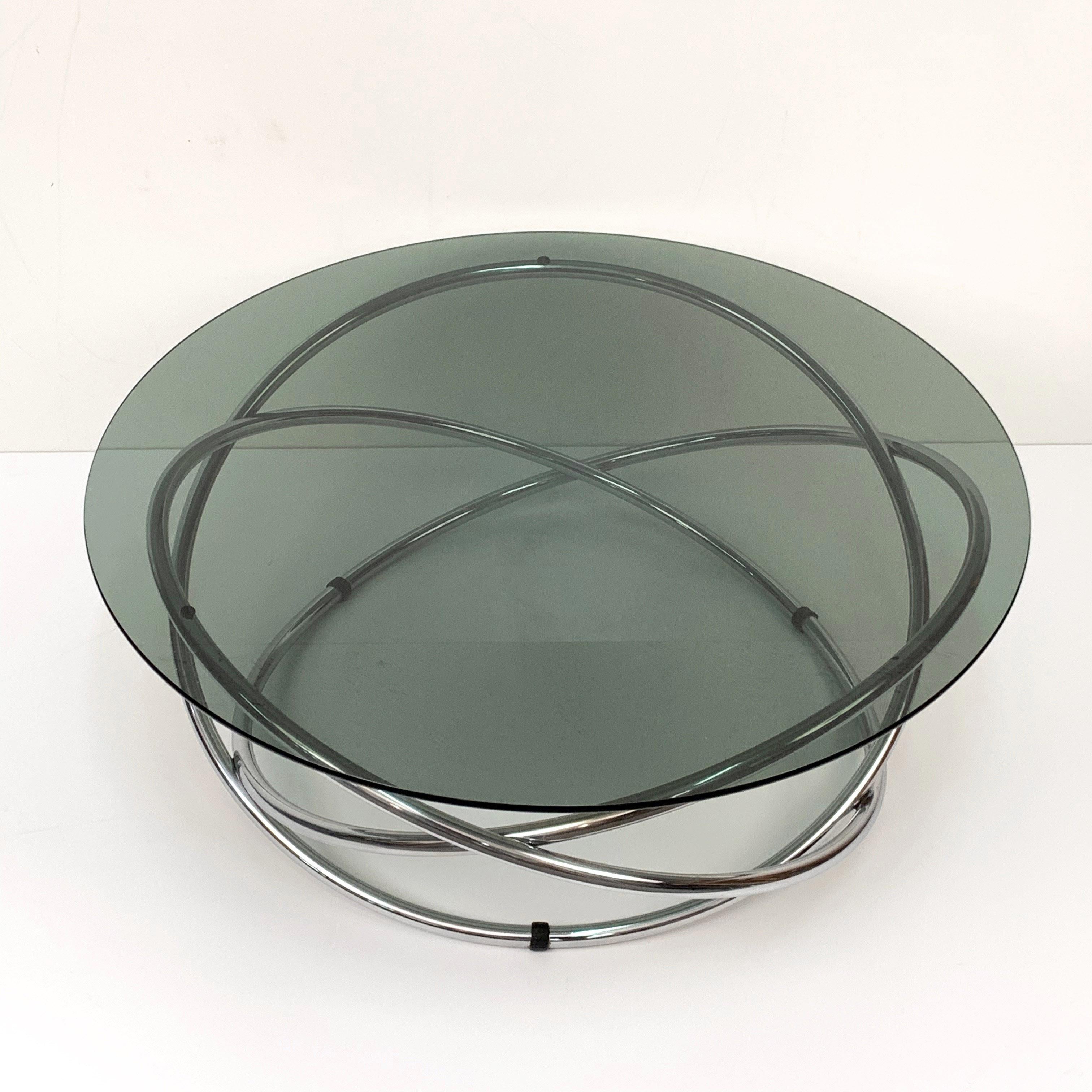 Beautiful round coffee table in chromed steel with smoked glass top made in Italy in the 1960s.

This atomic style Italian coffee table features a base with three tubular metal rings, and a smoked glass top.

A perfect example of 1960s design