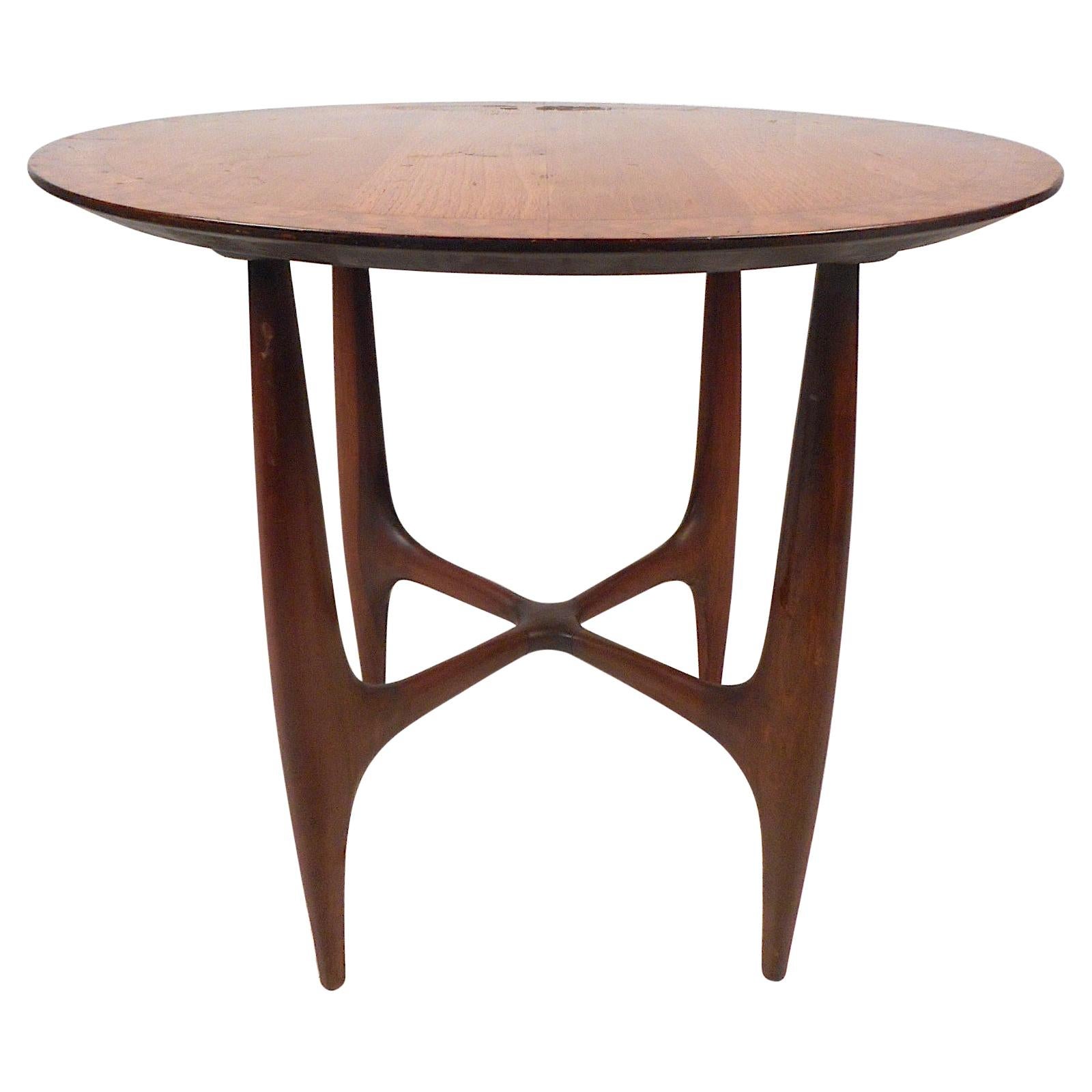 Stylish midcentury circular table. Spacious tabletop with a decorative burl-wood accent circling the edges. Sculpted wooden legs give this table a distinctive visual profile. Great addition to any modern interior. Please confirm item location with