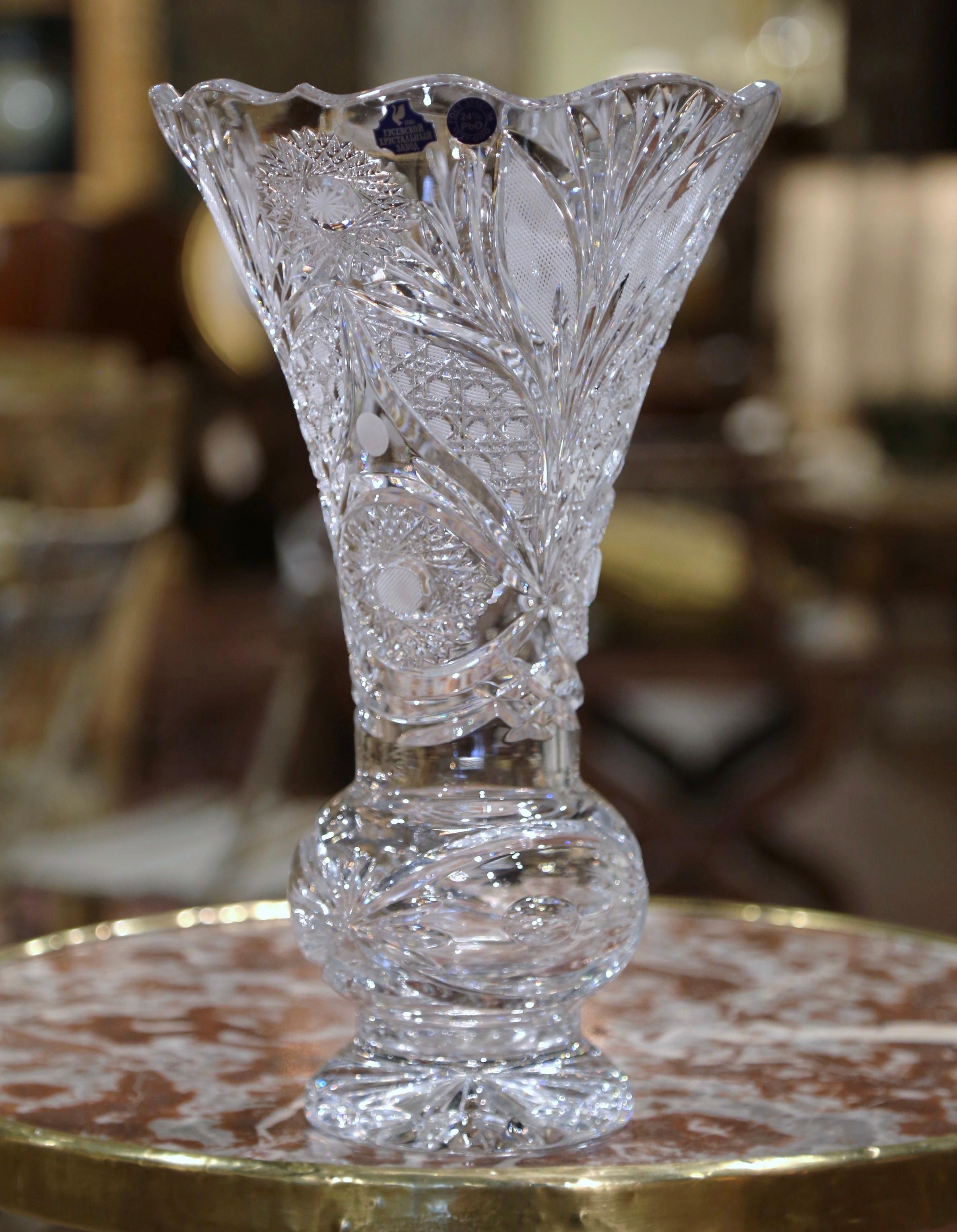 Decorate a console or buffet with this elegant crystal trumpet vase. Crafted in France, circa 1960, the large luxurious cut glass vessel is decorated throughout with etched geometric and vine decor. The piece stands on a sturdy circular base, a