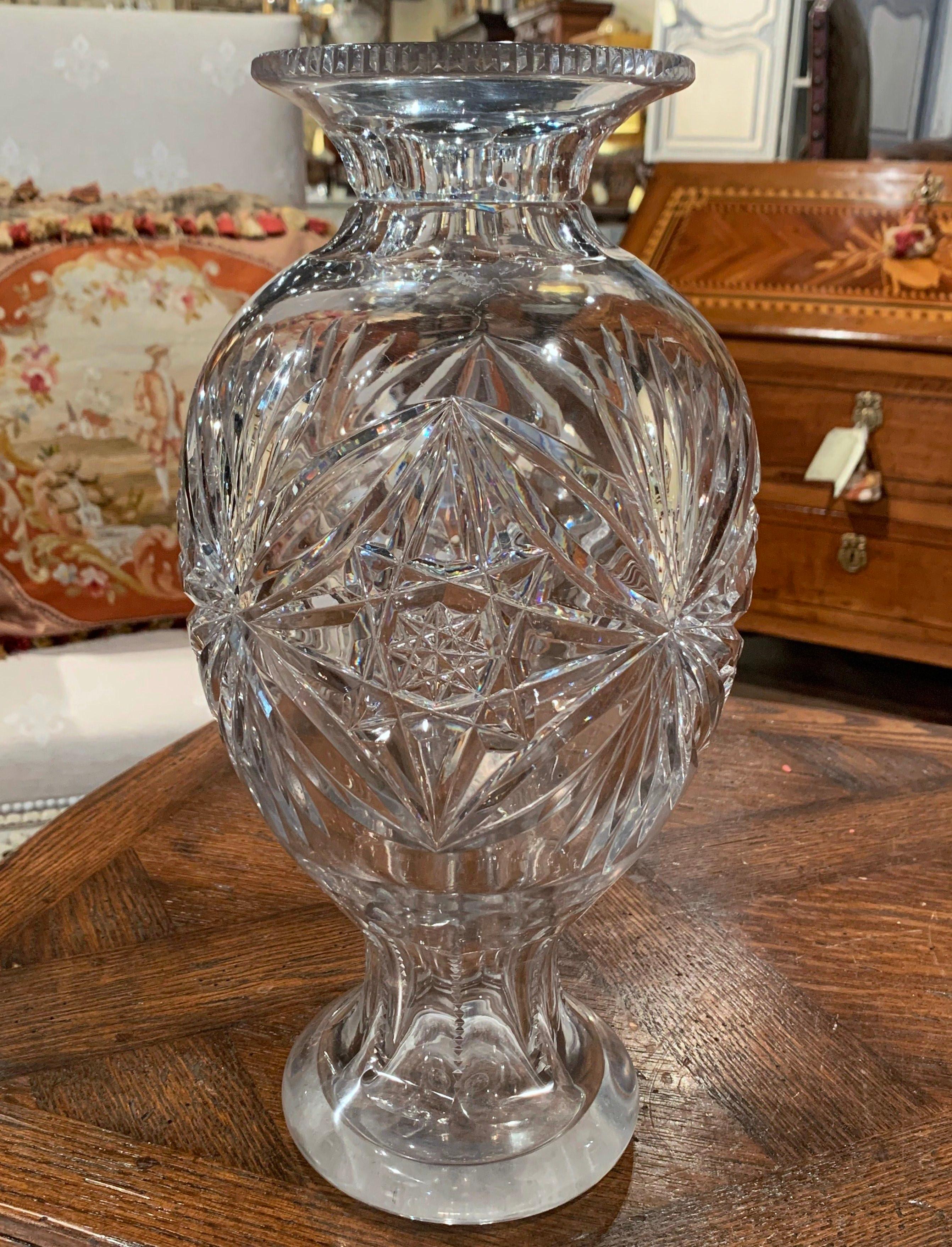 Decorate a console table or buffet with this elegant tall vase. Crafted in France circa 1970, the large luxurious cut glass vessel is round in shape and decorated throughout with leaf, star and sun decor. The thick heavy vase is in excellent