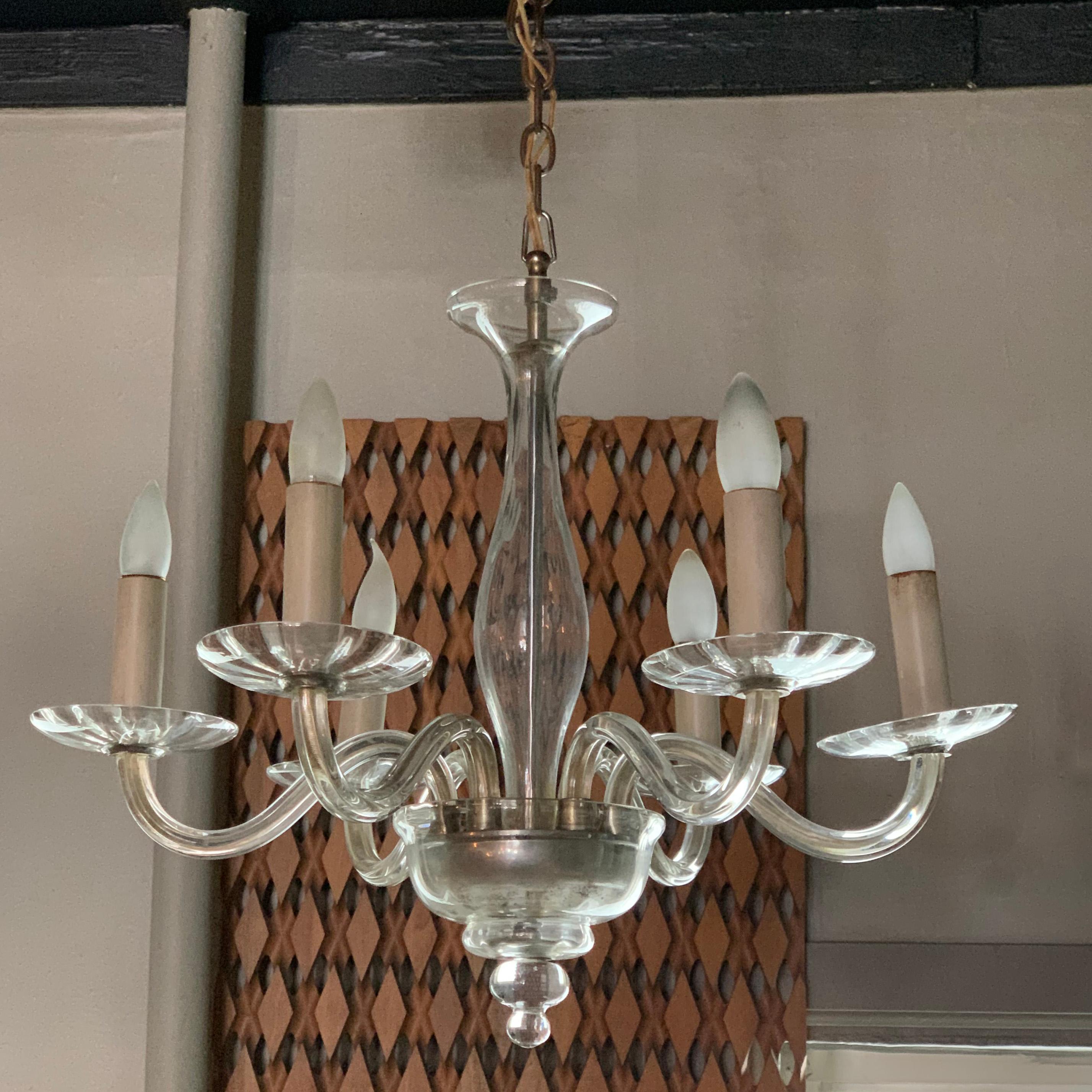 Italian, midcentury, clear Murano glass chandelier features 6 stems that can accept medium socket bulbs up to 40 watts each. The chandelier hangs with 24 inches of chain bringing it to approx 44 inches extended.