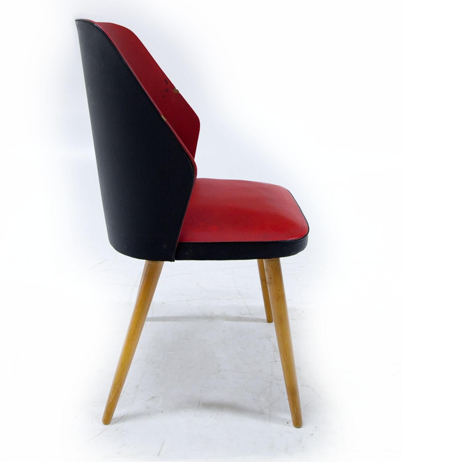 Midcentury club chair on conical wooden legs, upholstered with a black and red faux leather. Signs of age and use.