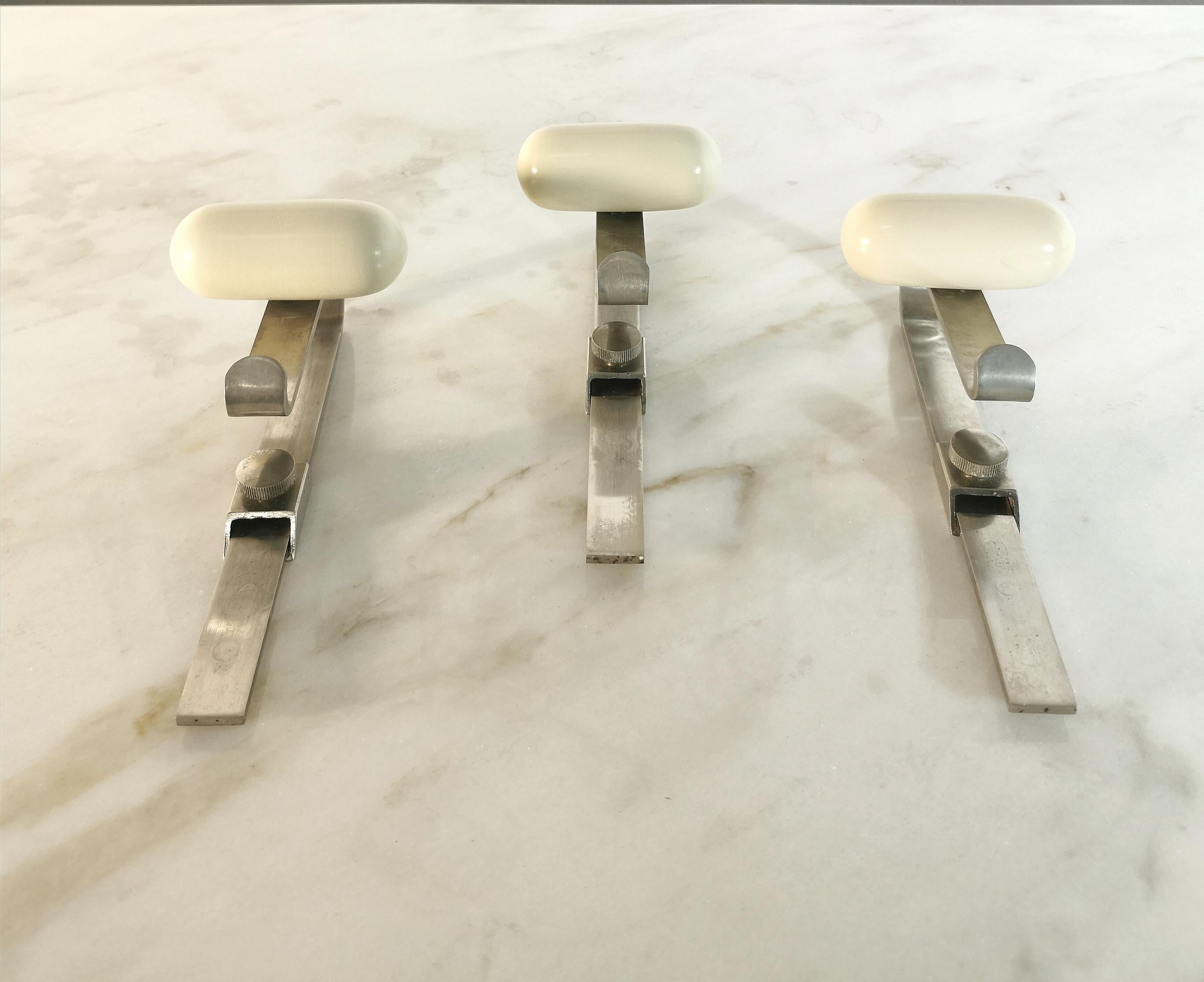 Set of 3 simpatic coat racks made in Italy in the 70s. 
Every single coat hanger is made of curved and brushed metal with an up and down movement accessory and enamelled wooden knob.